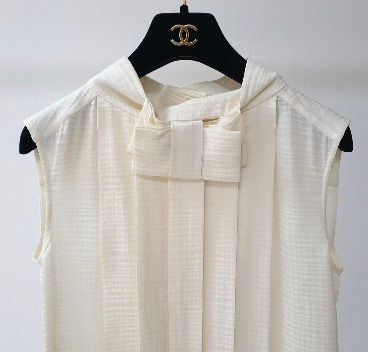 Chanel Ivory Sleeveless Pleated Silk top w/ Bow Detail & Globe buttons
Chanel Ivory Pleated Silk top w/ Bow Detail & Globe buttons 
Sz- 42 
 It has long pleats from the collar down the length of the shirt and a flat bow detail on the neck. 
There