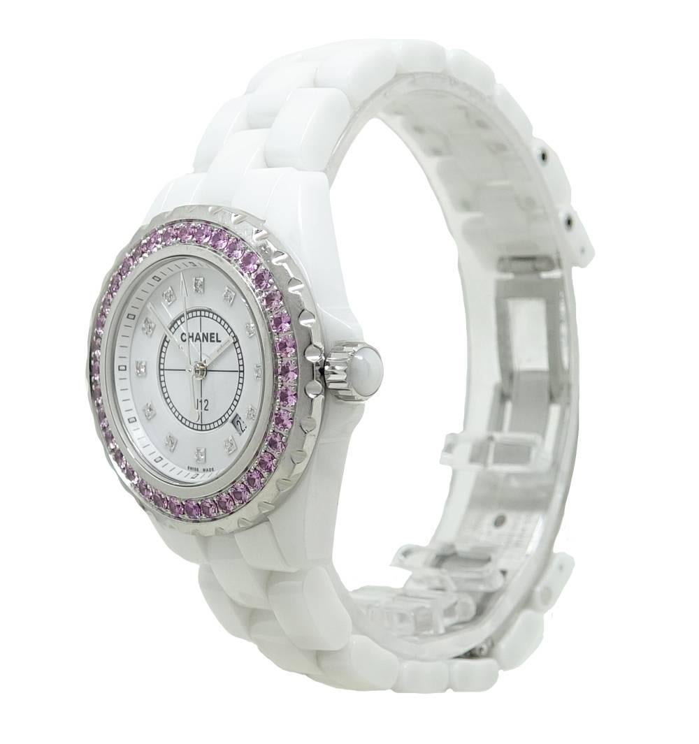 This Stunning Chanel J12 White Ceramic Watch Has 36 Beautiful Pink Sapphires Set In The Bezel and Sparking Diamonds In Place Of The Markers. A Date Aperture  Is Found Between The 4 And 5 Markers, As Well As A Center Second Hand. This 33mm Watch Has
