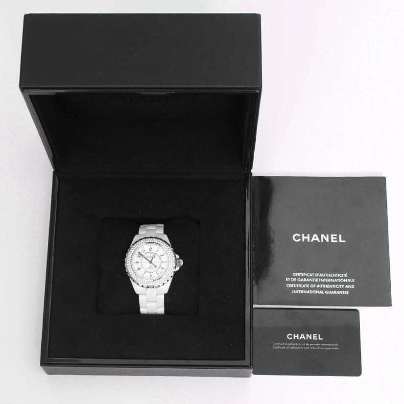 Chanel J12 White Ceramic Automatic 38mm  Diamond Watch H0969 -  Automatic winding. White ceramic case with 2-row diamond bezel (38mm diameter). White dial with black Arabic numerals; date between 4 & 5 o'clock. White ceramic bracelet. Pre-owned with
