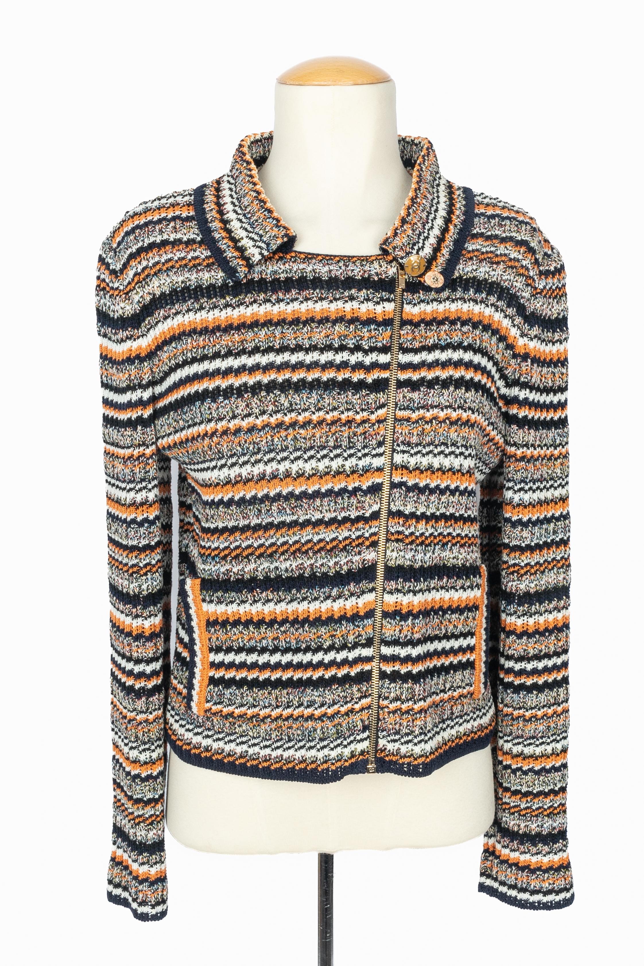 CHANEL - (Fabriqué en France) Veste en maille dans les tons orange, bleu marine et blanc. Taille 36FR indiquée. Collection 2017 Resort Paris-Cuba sous la direction artistique de Karl Lagerfeld.

Condit :
Très bon état.

Dimensions :
Largeur des