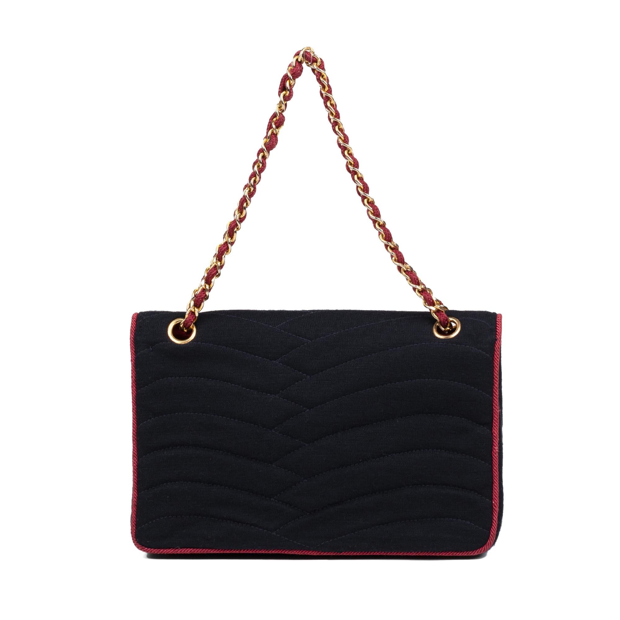 
Chanel, Haute Couture Collection, 
CIRCA 1970 Classic stitched navy jersey bag, red cord, clasp and lined handle gold metal chain, fuschia ottoman lining.
 Dimensions: 17 * 25 * 7 
Good general condition