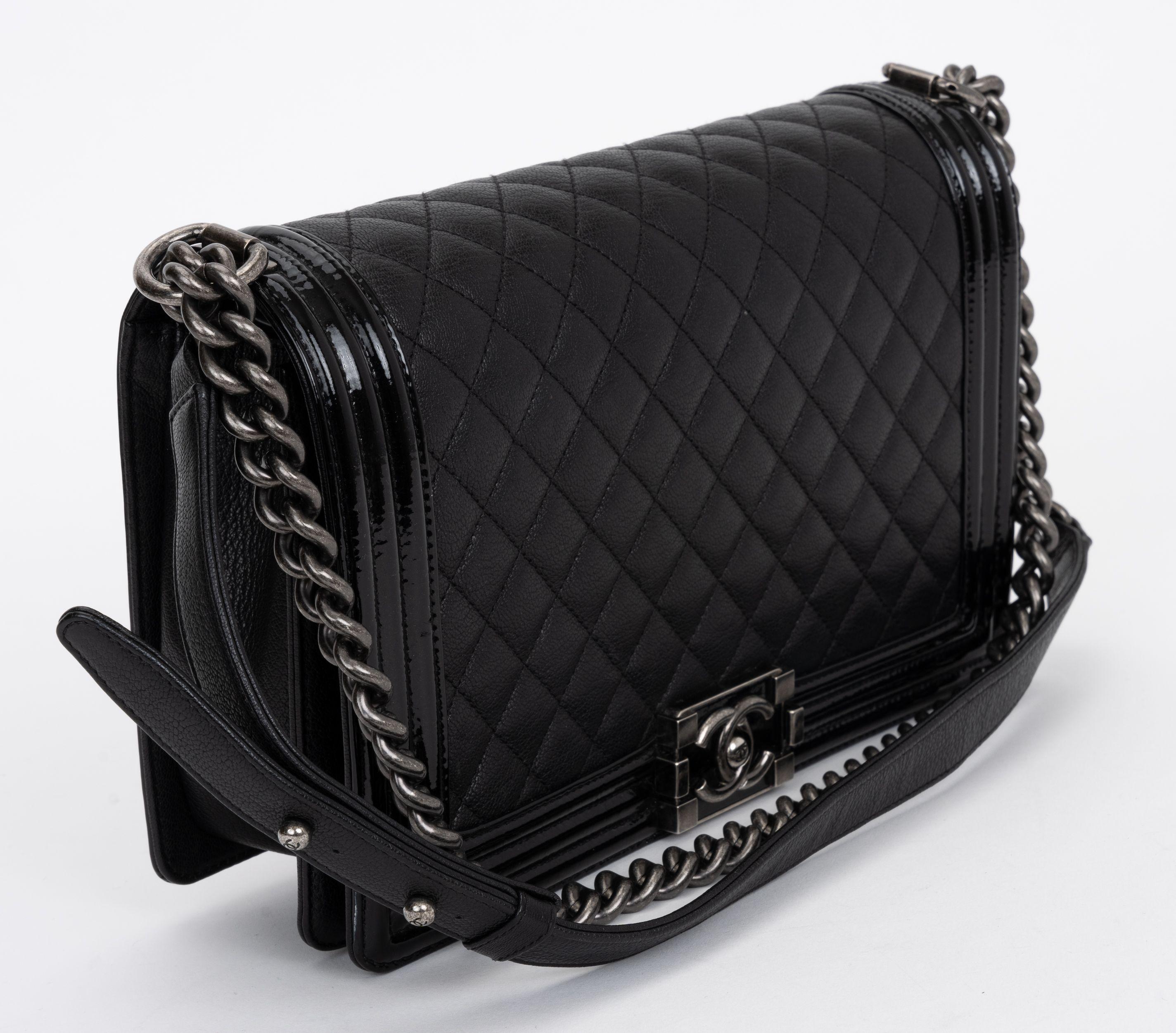Chanel Calfskin Double Stitch Jumbo Boy Flap in black. The shoulder bag is crafted of diamond quilted calfskin leather with linear quilted sides in black. The bag features an aged ruthenium chain link shoulder strap and a boy squared Chanel CC push