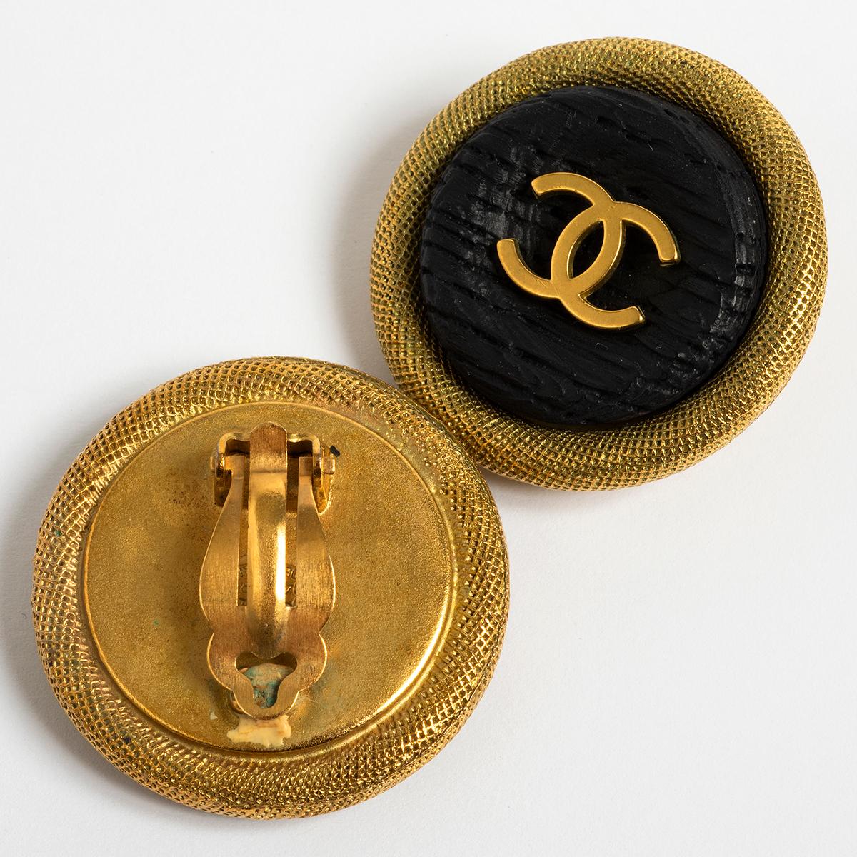 Our vintage Chanel clip on earrings feature a gold metal base and clip, with wood effect centre and prominent CC central logo. These earrings are date stamped Spring 1994. Measuring 35.5mm across, and 8mm deep excluding clip, these are presented in