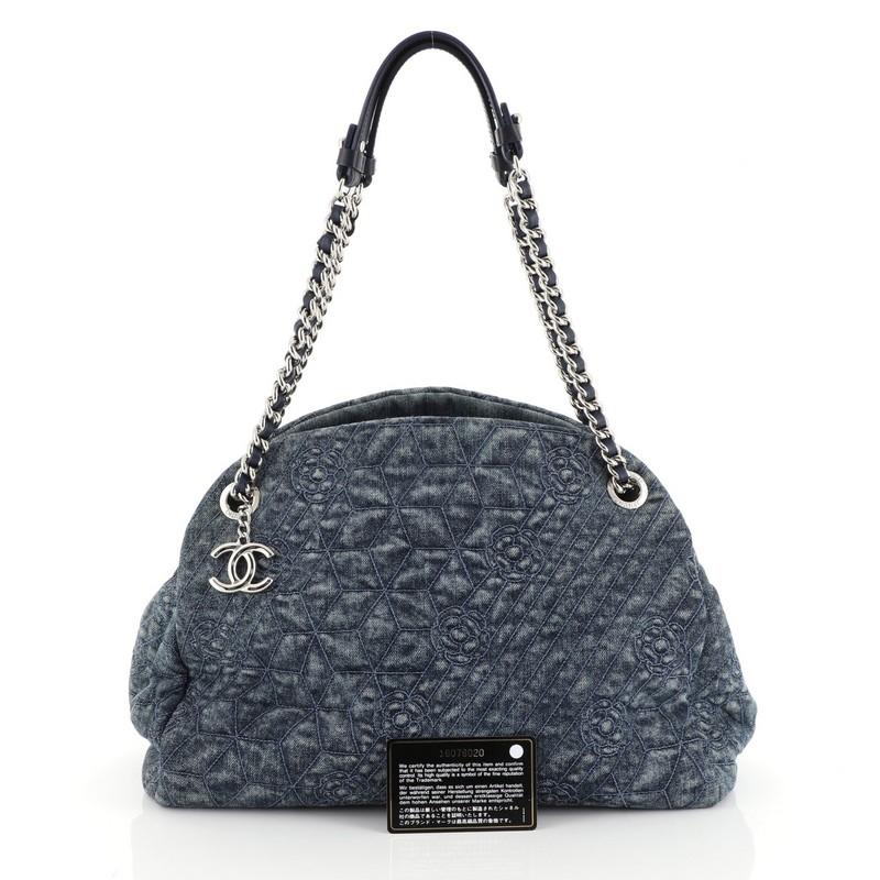 This Chanel Just Mademoiselle Bag Camellia Denim Medium, crafted from blue camellia denim, features woven-in leather chain straps, protective base studs, and silver-tone hardware. It opens to a blue fabric interior with two open compartments and a