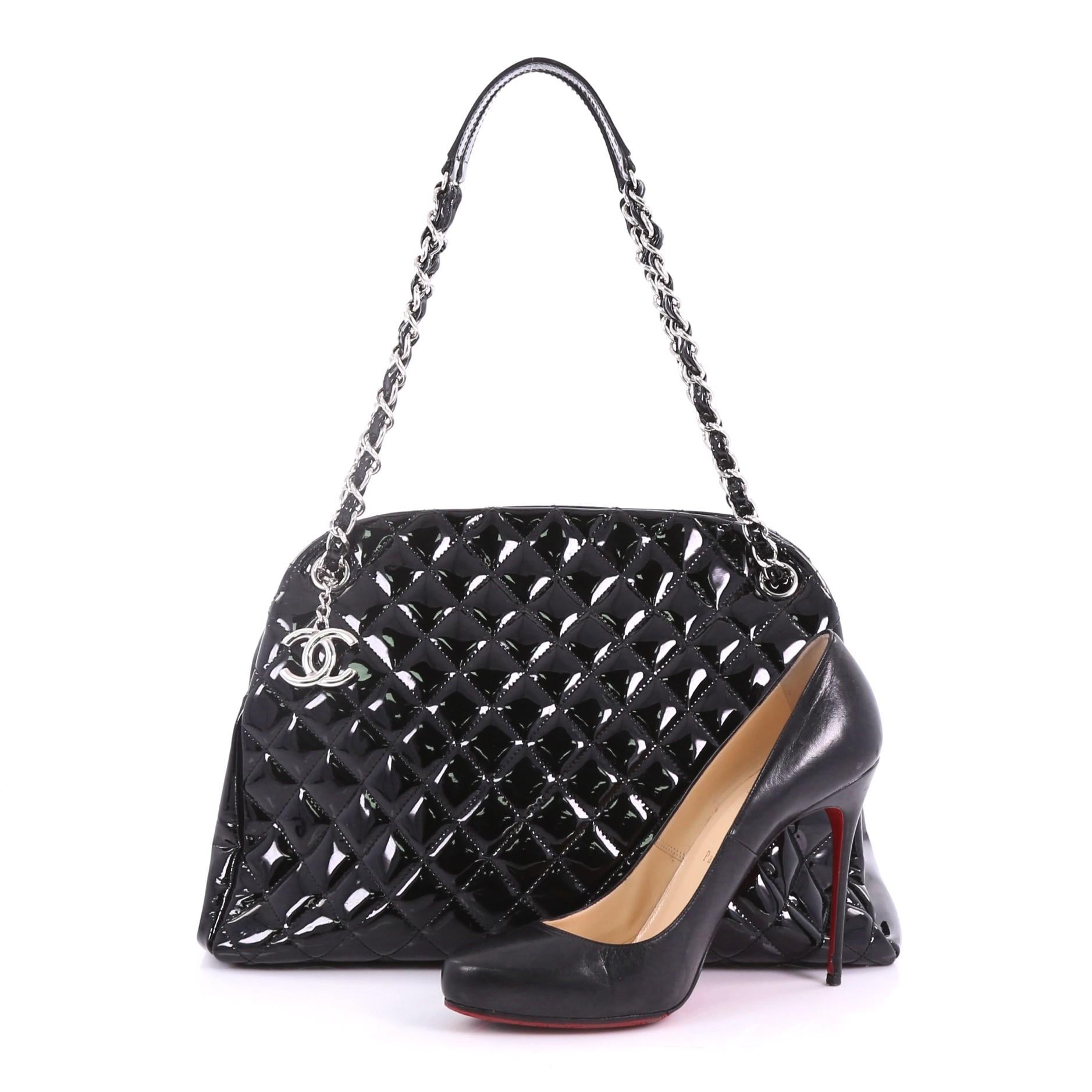 This Chanel Just Mademoiselle Handbag Quilted Patent Large, crafted in black quilted patent leather, features dual woven in leather chain link straps, and silver-tone hardware. Its top magnetic snap closure opens to a black fabric interior with