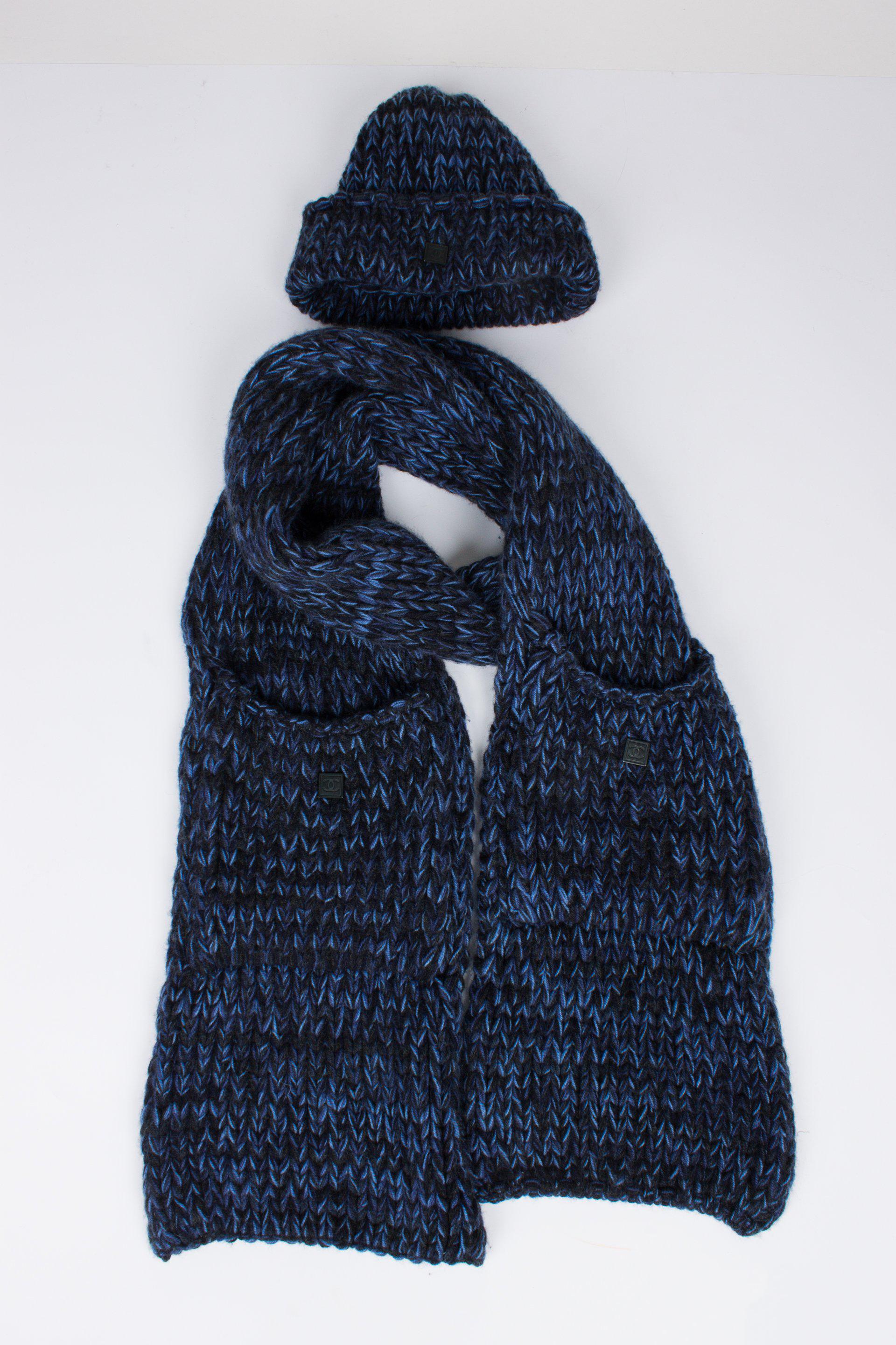 Two-piece Chanel set; a knitted hat and a scarf, both in a chunky crochet knit in black and blue cashmere. The hat has a round shape and a fold over where you will find a square black metal tag with CC-logo.

The scarf has an enormous length, it