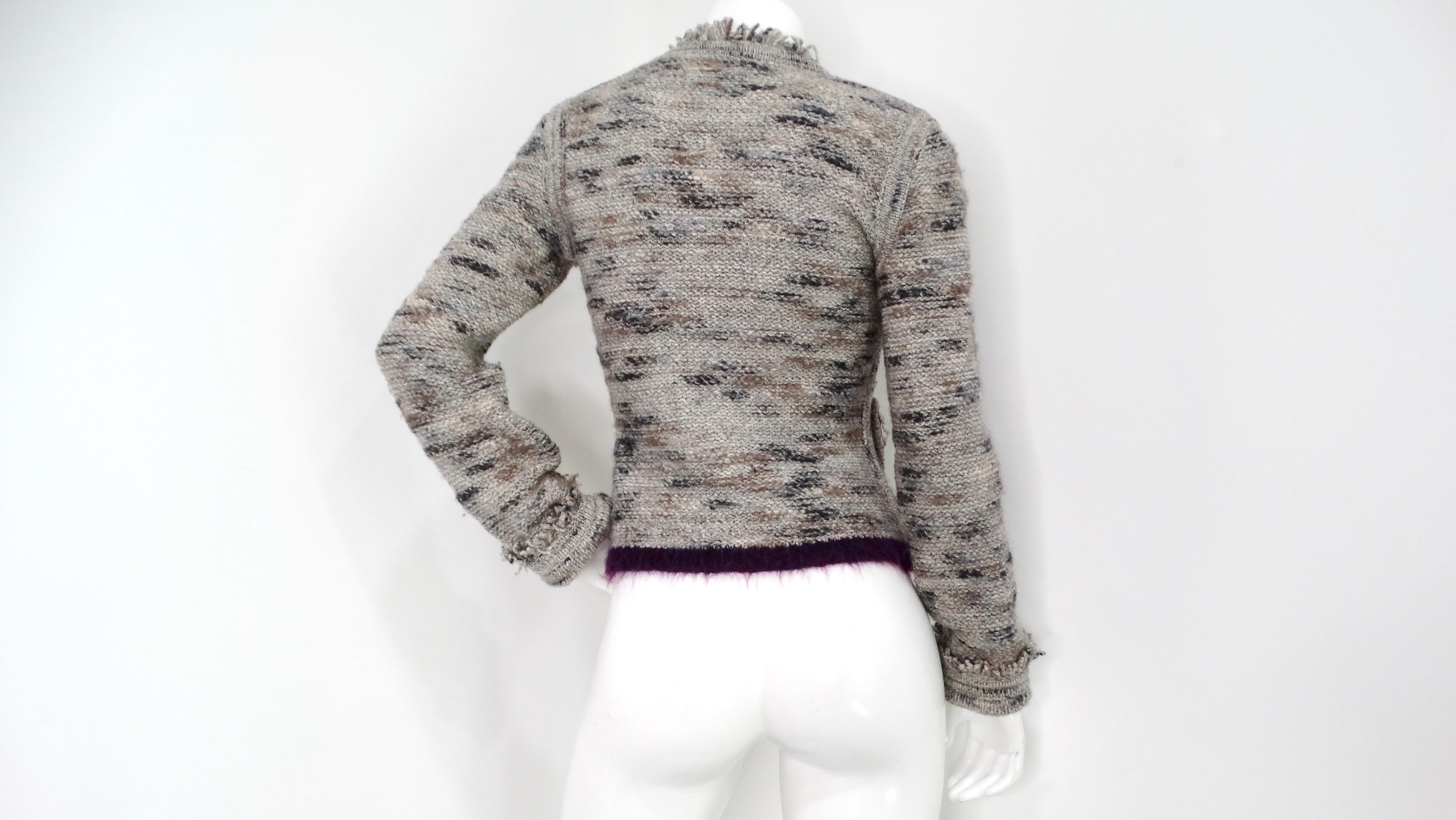 The Chanel Knit Wool Blend Fringe Cardigan from circa 1999 is a quintessential piece that embodies the luxury and timeless elegance associated with the iconic fashion house. Crafted from a plush multi-grey wool blend, this cardigan offers a cozy yet