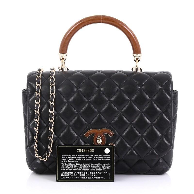 This Chanel Knock on Wood Top Handle Bag Quilted Lambskin Mini, crafted in black quilted lambskin, features a wood top handle, woven-in leather chain strap and gold-tone hardware. Its turn-lock closure opens to a black leather interior. Hologram
