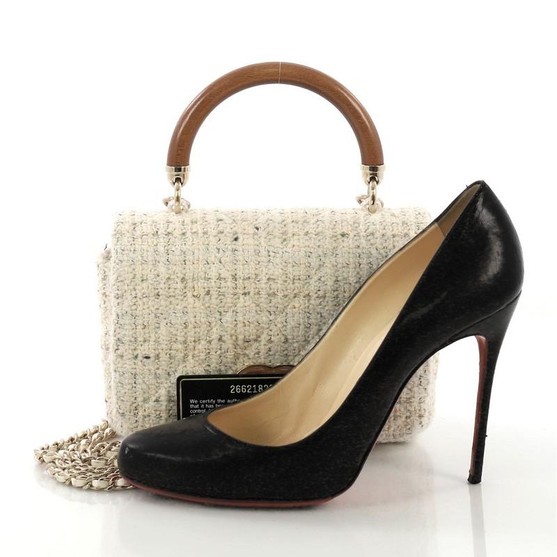 This Chanel Knock on Wood Top Handle Bag Quilted Tweed Mini, crafted in cream quilted tweed, features a wood top handle, woven-in leather chain strap and gold-tone hardware. Its turn-lock closure opens to a cream fabric interior. Hologram sticker
