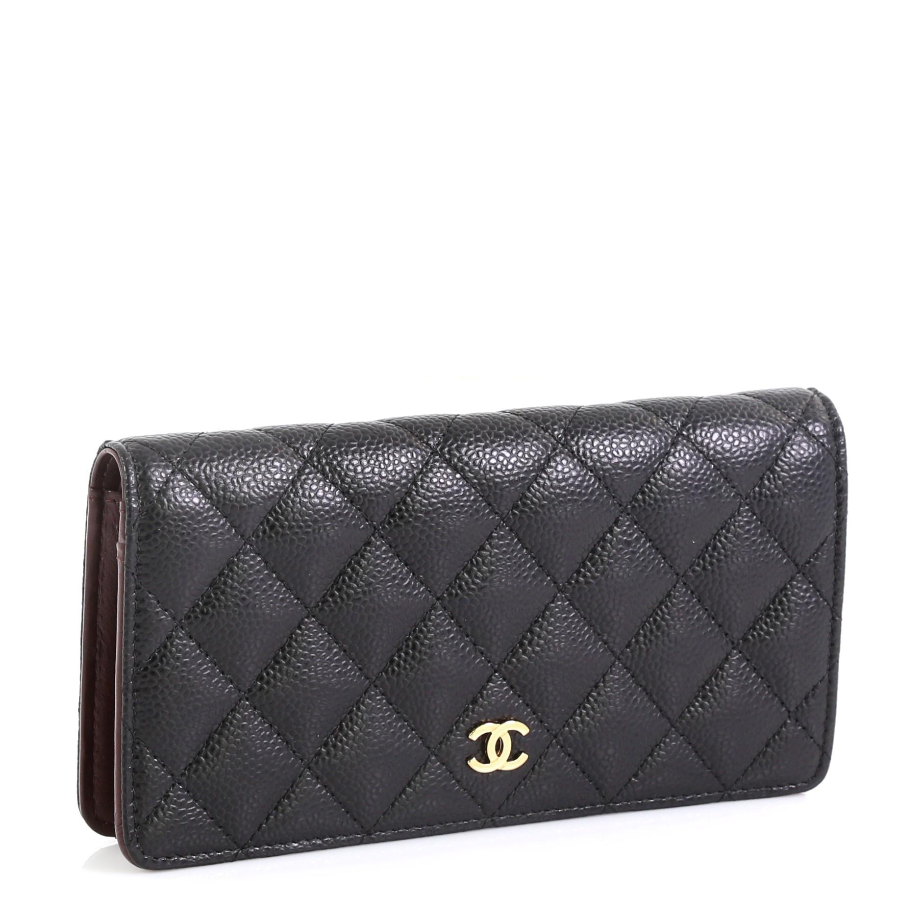 This Chanel L-Yen Wallet Quilted Caviar, crafted from black quilted caviar leather, features small CC logo, back slip pocket, and gold-tone hardware. It opens to a red leather interior with multiple card slots, long flat pockets, gusseted