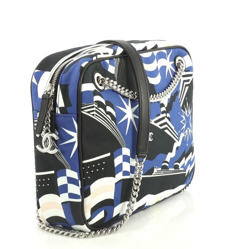This Chanel La Pausa Bay Camera Case Bag Printed Canvas Small, crafted from blue printed canvas, features chain link strap with leather pad and silver-tone hardware. Its zip closure opens to a blue fabric interior with zip pocket. Hologram sticker