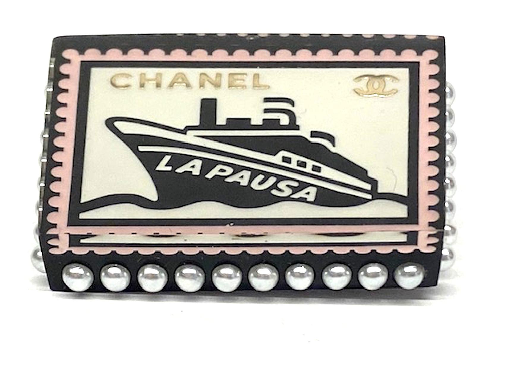 A charming Chanel lucite and faux pearl pin from the Spring 2018 collection. Bottom layer of pin is black lucite with sides set with faux pearls. Top is clear lucite. Sandwiched in-between is a black and white image of a cruise ship with 