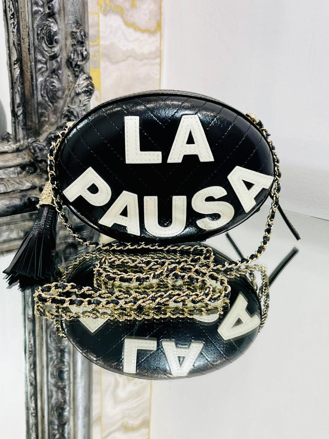 Chanel La Pausa Villa Leather Bag

Oval hard case bag in black chevron Lambskin leather with contrasting white, stitched wording 'LA PAUSA'. 

Gold leather and chain shoulder/crossbody strap. Gold 'CC' capped logo leather tassel. Rare find in black