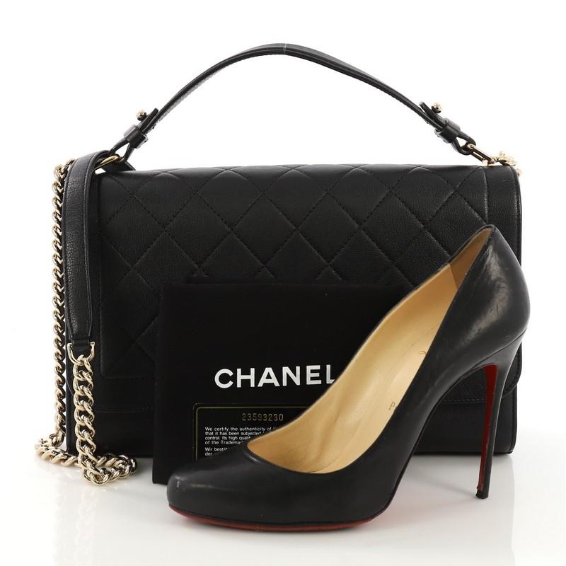 This Chanel Label Click Flap Bag Quilted Calfskin Large, crafted from black quilted calfskin, features leather top handle, chain link strap, and gold-tone hardware. Its push-lock closure opens to a beige fabric interior with side zip pocket.
