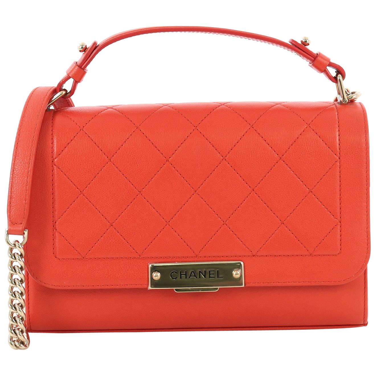 This Chanel Label Click Flap Bag Quilted Calfskin Medium, crafted from red quilted calfskin, features leather top handle, chain link strap, and gold-tone hardware. Its push-lock closure opens to a beige fabric interior with side zip pocket. Hologram