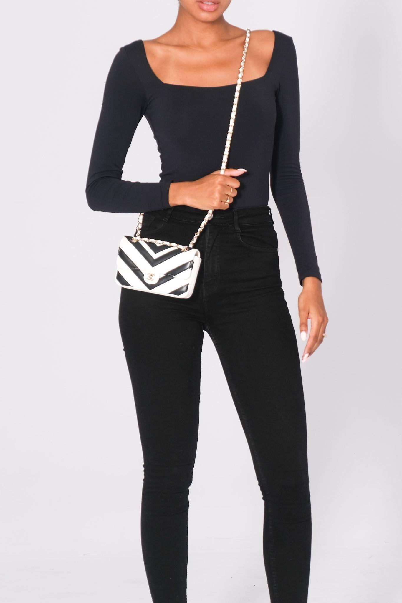 This shoulder bag is made of chevron lambskin leather in black and white. The shoulder bag features a gold chain-link leather-threaded shoulder strap and a front flap with a gold tone classic CC turn-lock. The flap opens to a white fabric interior