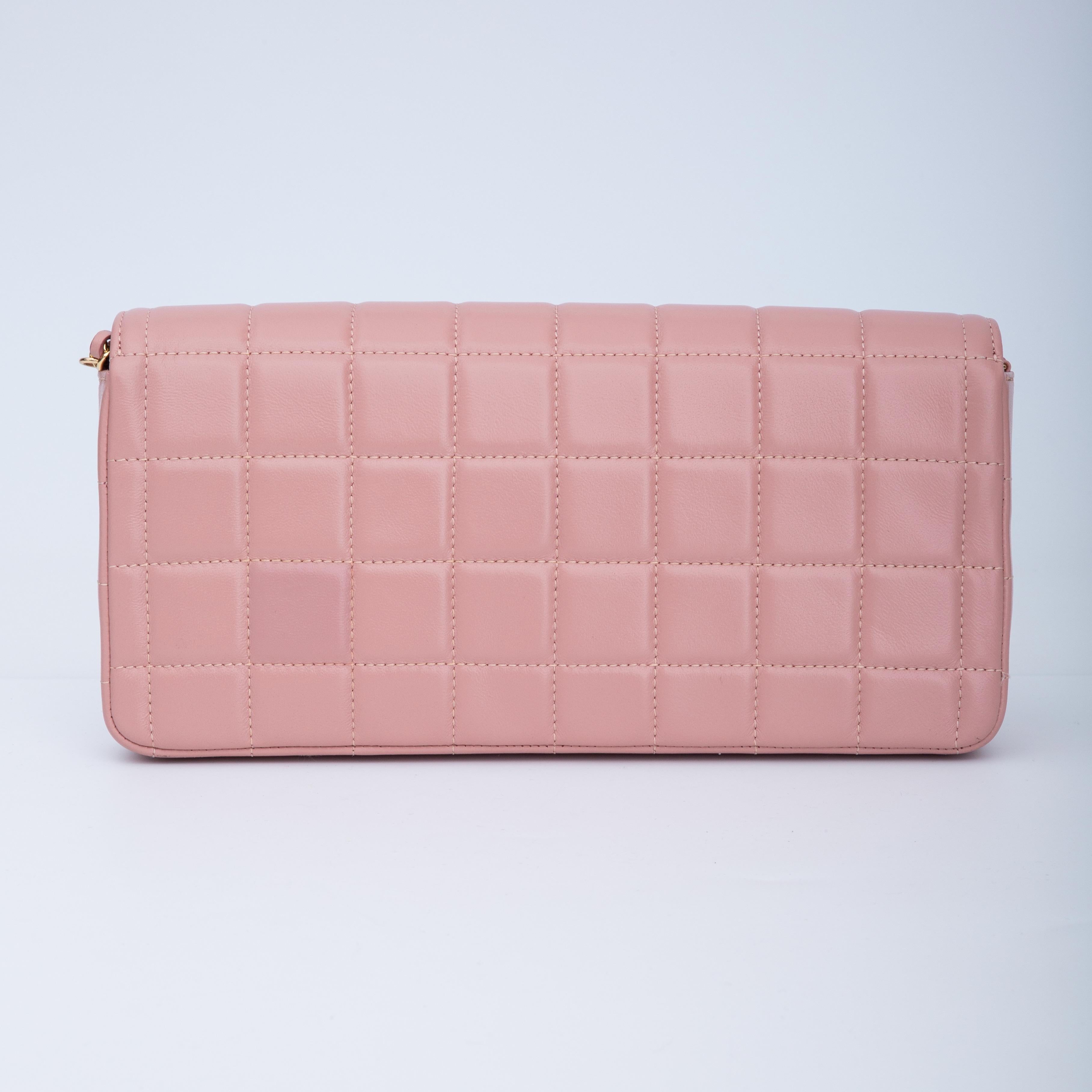 This shoulder bag is constructed of fine square quilted lambskin leather in pink. The bag features a short frontal flap with a gold CC turn lock and a gold shoulder chain threaded with matching leather. The frontal flap opens to a matching leather