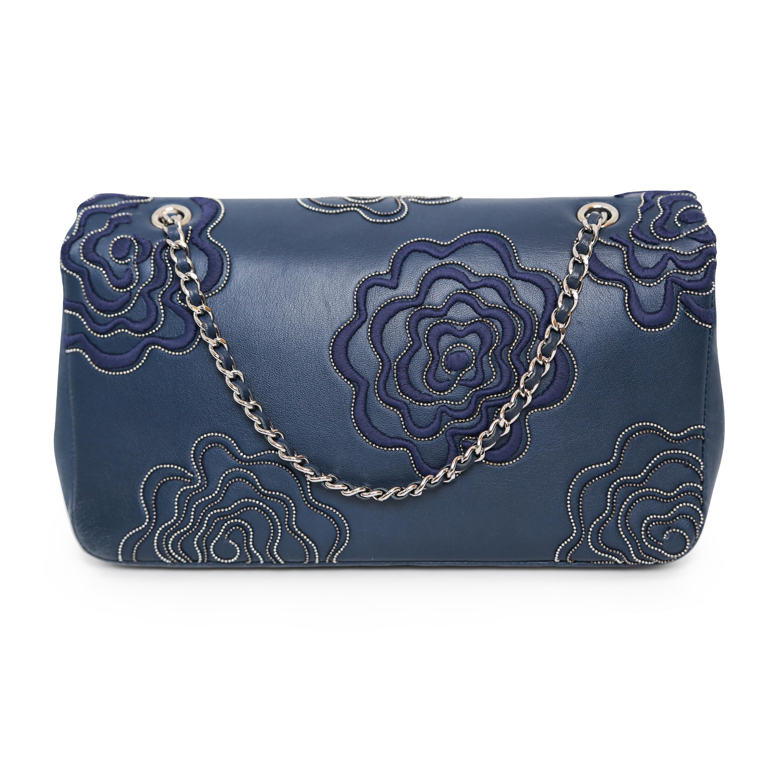 This Chanel flap bag features stunning embroidered and beaded camellias. There is an internal zippered pocket. It is in excellent condition.

*The front flap features the iconic CC logo with a silver-tone twist lock
*Silver hardware
*Lined with navy