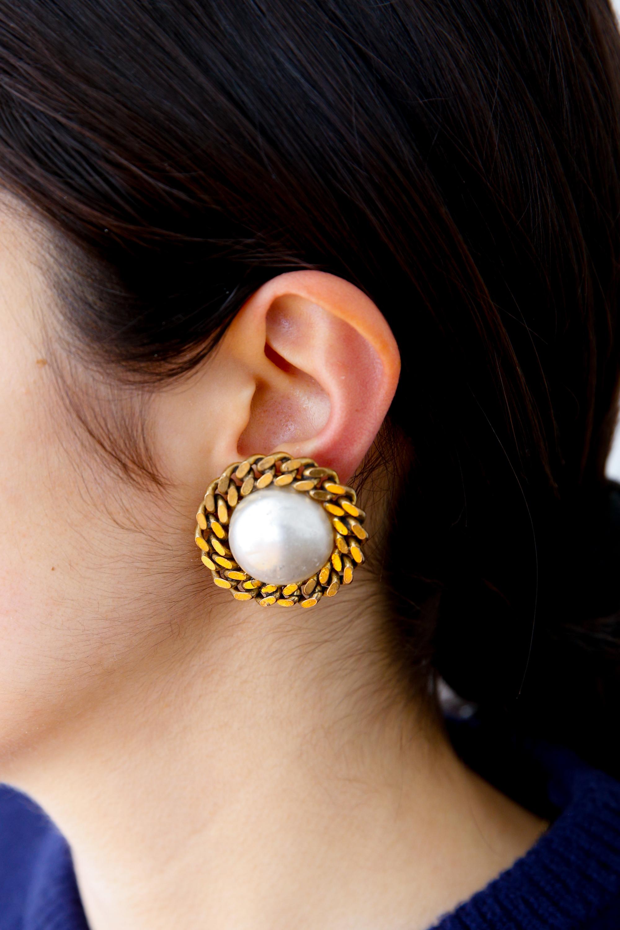 Chanel Ivory faux-pearls large round earrings featuring a large gold-tone chain outline, a large central faux-pearl bead, and a back plaque pitted. They come as a pair. 
Delivered in original box.
Circa 1980s  Made in France
Diameter: 1.30in.