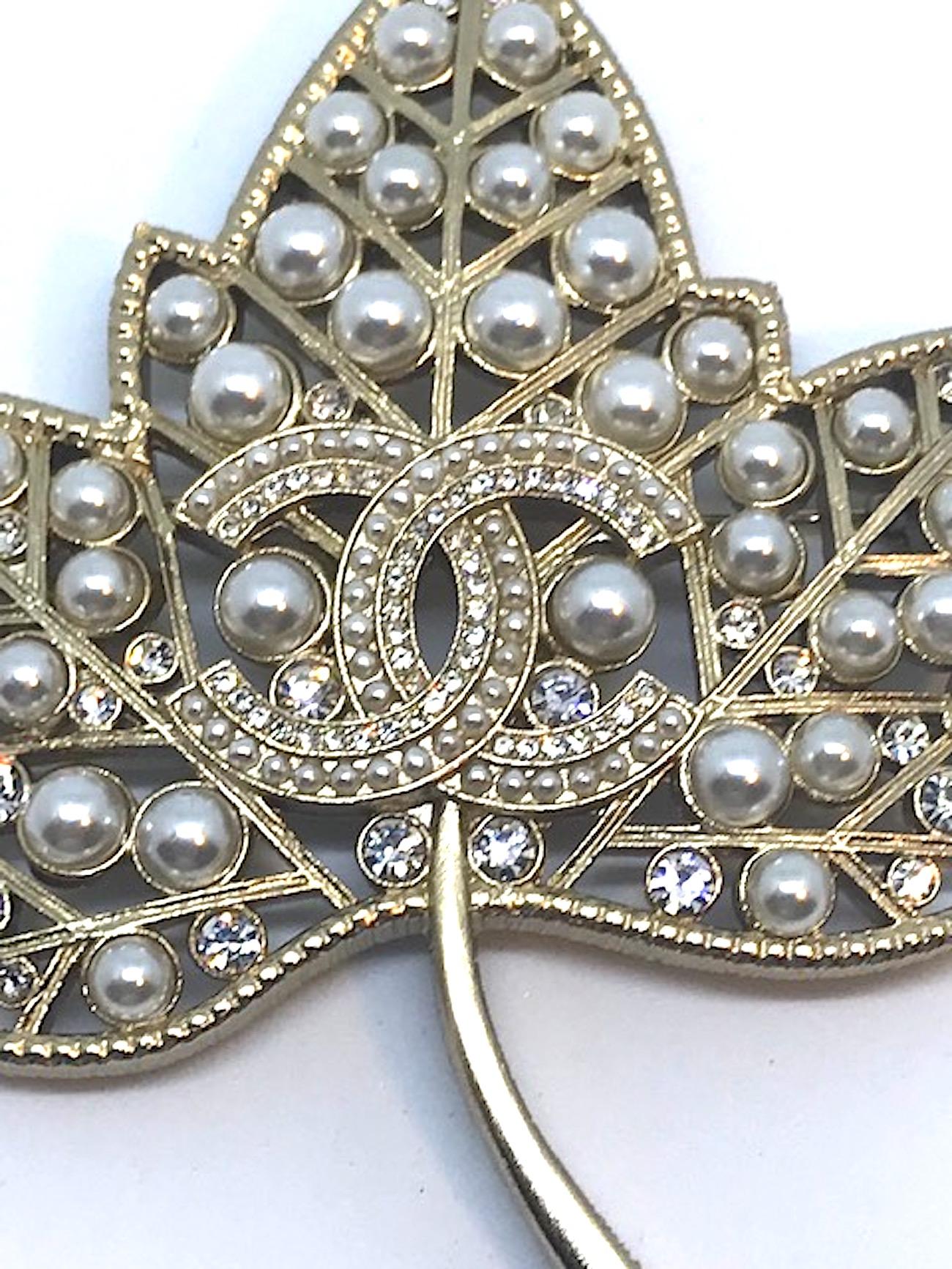 A beautiful and large Chanel pin in the form of a Sycamore leaf from the 2018 Spring collection. Cut out body, veins and stem of pin in satin gold and set with crystal rhinestones and faux pearls. Central interlocking CC logo set with mini seed