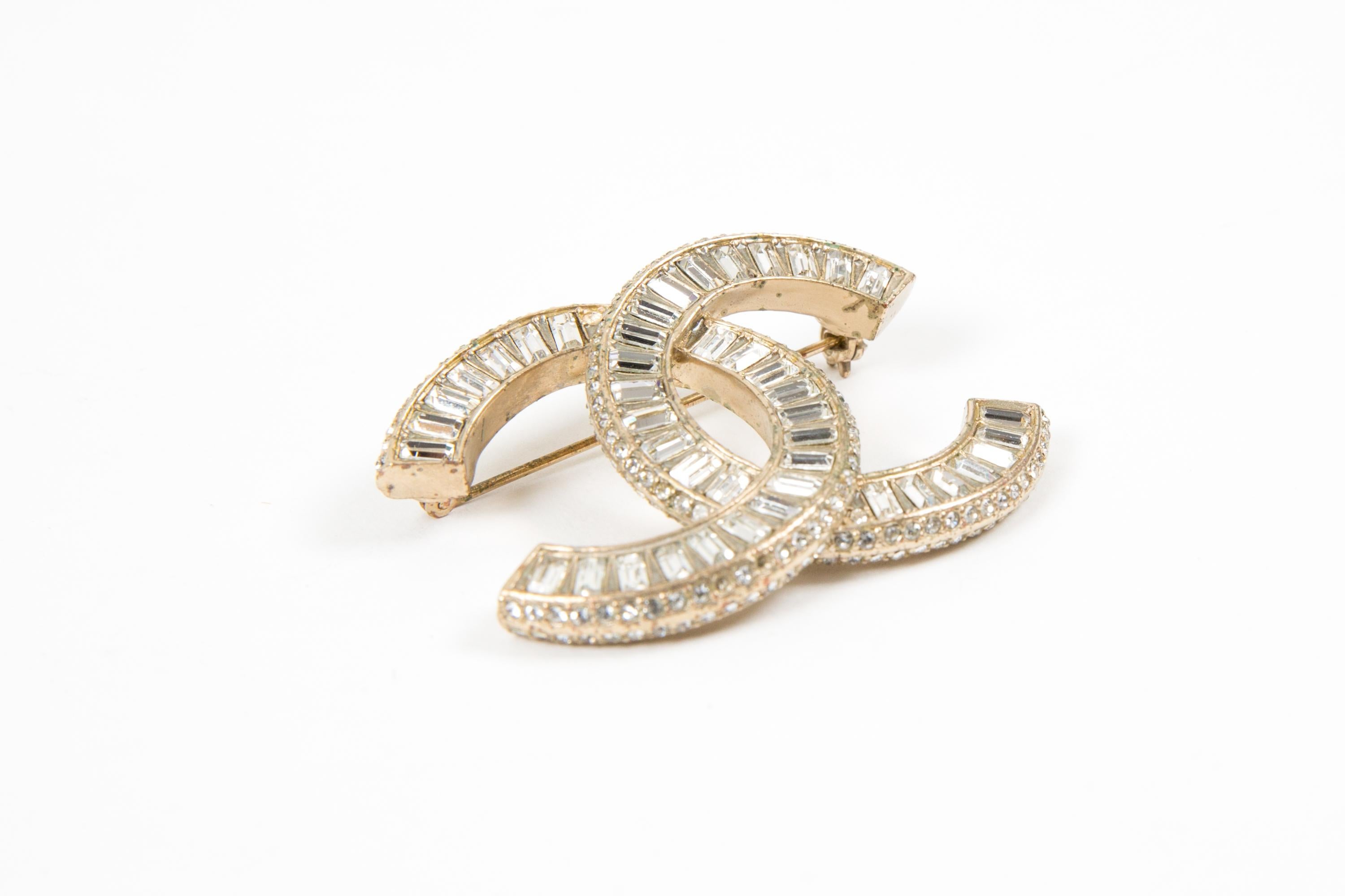 Chanel large gold-tone and crystal embellished CC brooch featuring a gold-tone signature interlocking CC logo, white crystal embellishment, a back bar-pin a logo plaque. 
Circa 2015.
Good vintage condition. Made in France. 
Length: 1.5in.