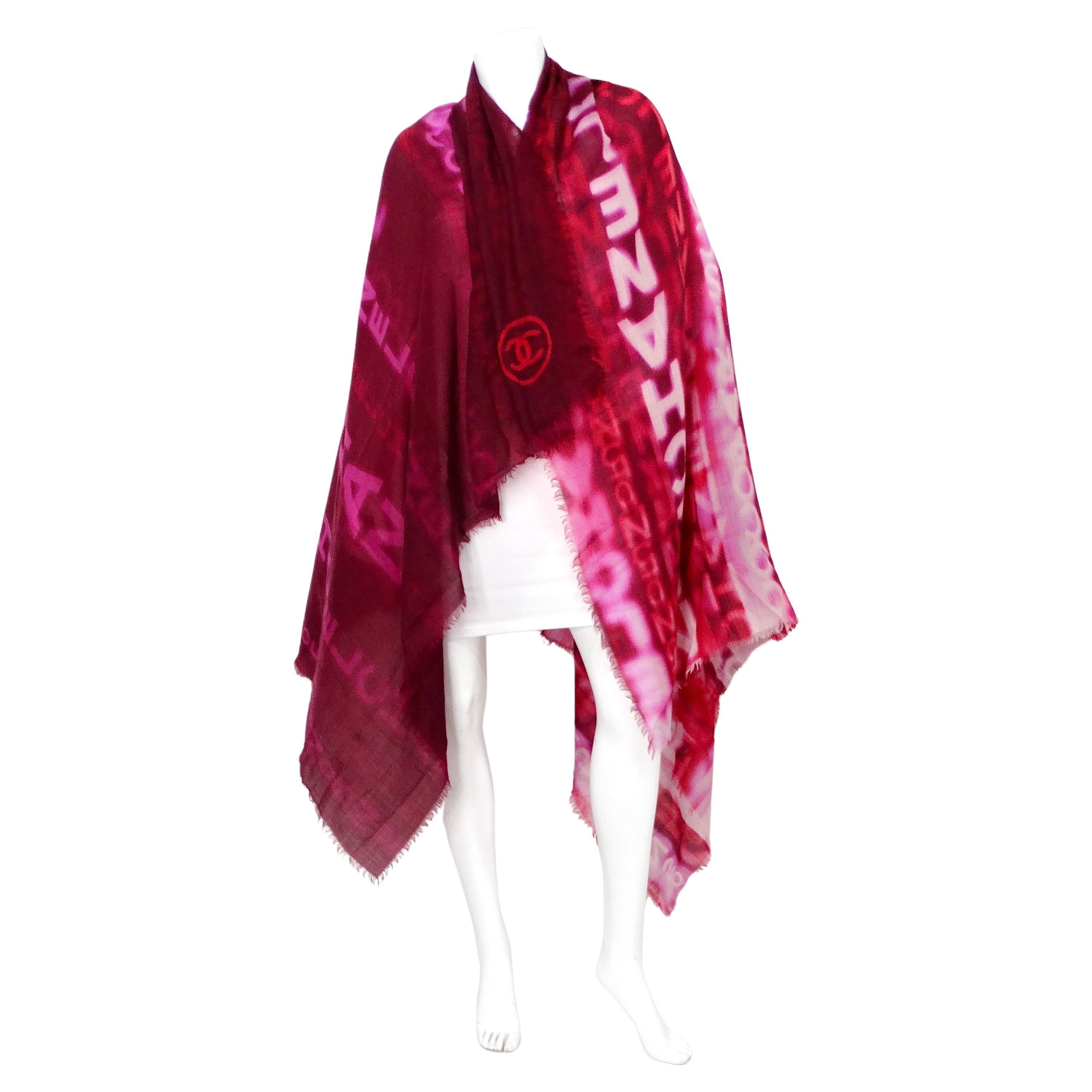The Chanel Large Logo Print Purple & Red Fringe Scarf is a luxurious accessory that effortlessly combines elegance and boldness. Crafted from high-quality fabric, this scarf features a striking blend of purple, pink, and red hues, creating a vibrant
