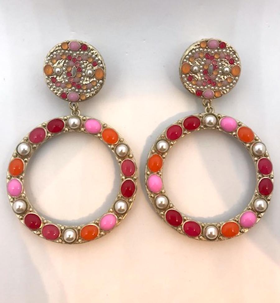 A great pair of large pendant hoop earrings from 2018. The pale gold finish perfectly sets off the pastel orange, light and dark pink and fascia-red cabochons and pearls. The top button of the earrings are set with mini versions of the same color