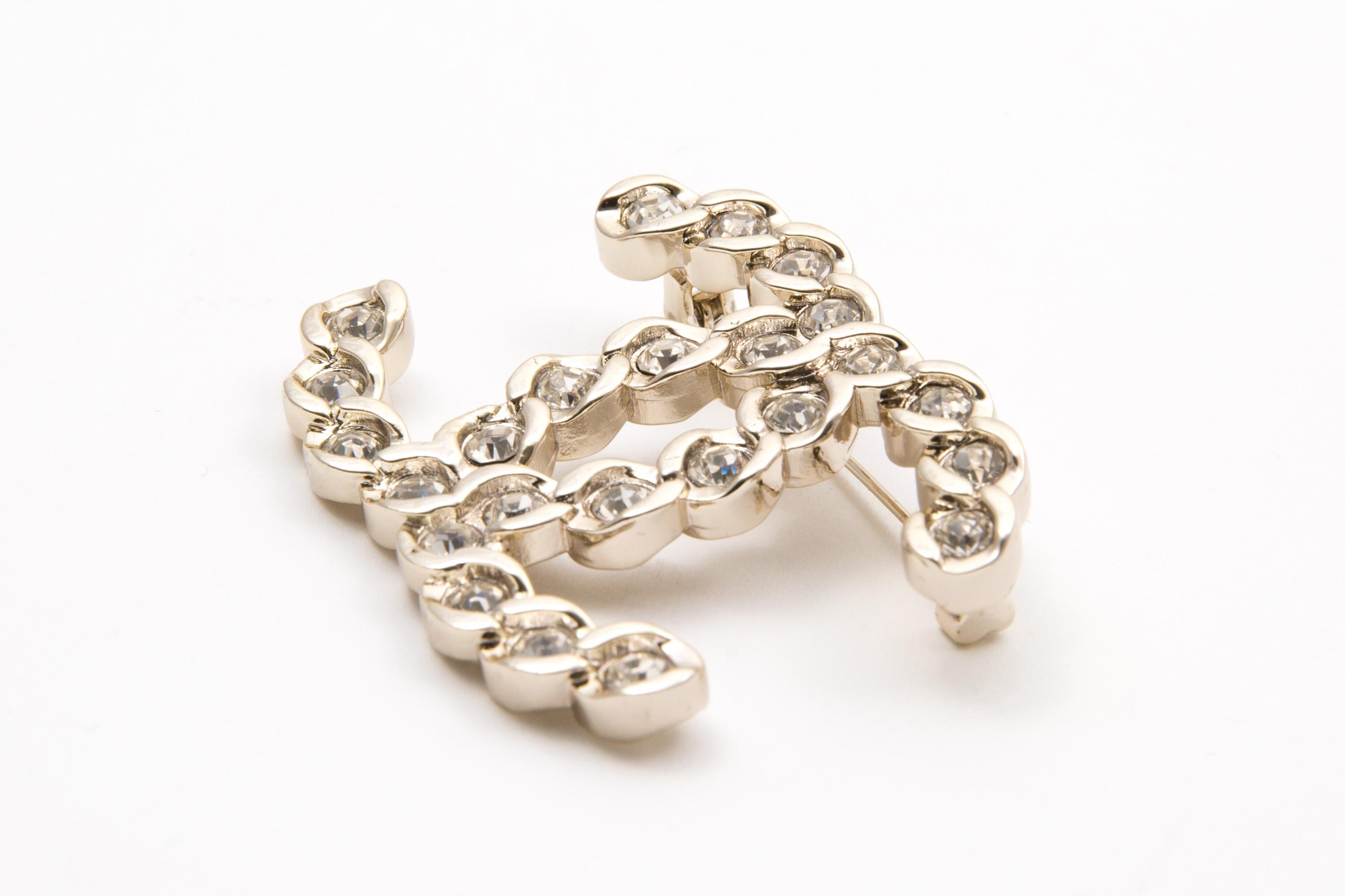 Chanel large silver-tone and crystal embellished CC brooch featuring a silver-tone signature interlocking CC logo, white crystal embellishment, a back bar-pin a logo plaque. 
Circa 2010s.
Good vintage condition. Made in France. 
Length: 1.5in.