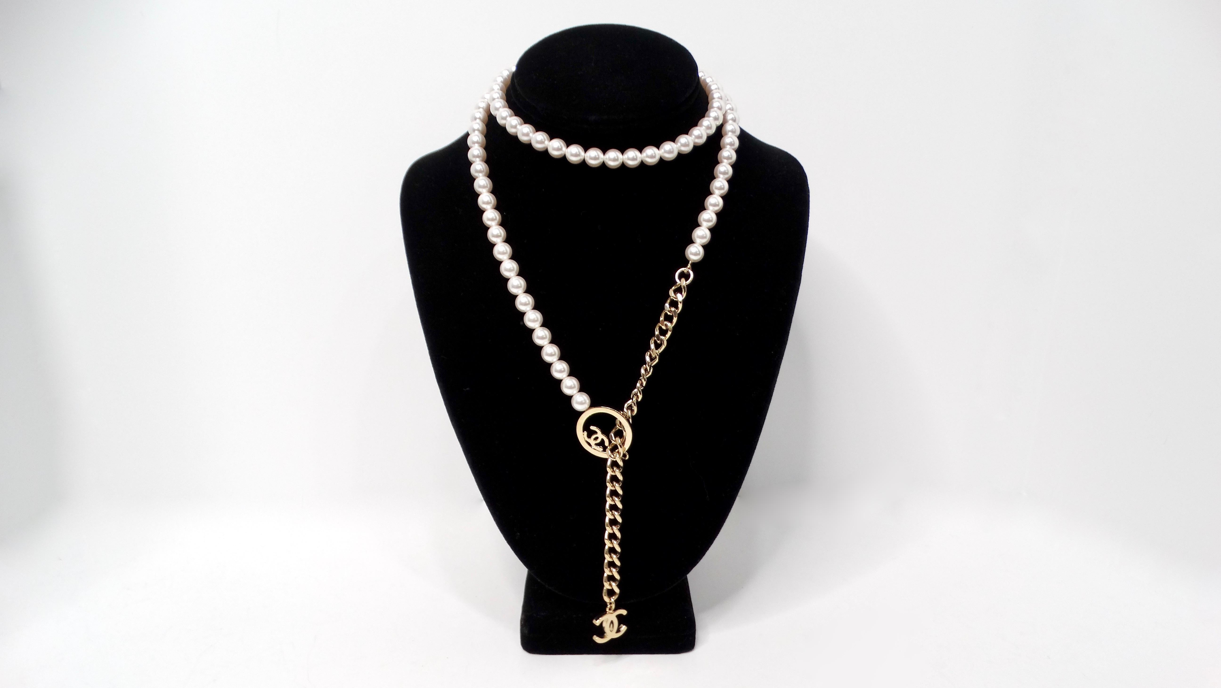 The Chanel Lariat Pearl Strand & Gold-Tone Chain Interlocking CC Logo Necklace is a stunning piece that seamlessly blends elegance and modern chic. Crafted with a luxurious faux pearl strand, this necklace gracefully drapes around the neck, exuding
