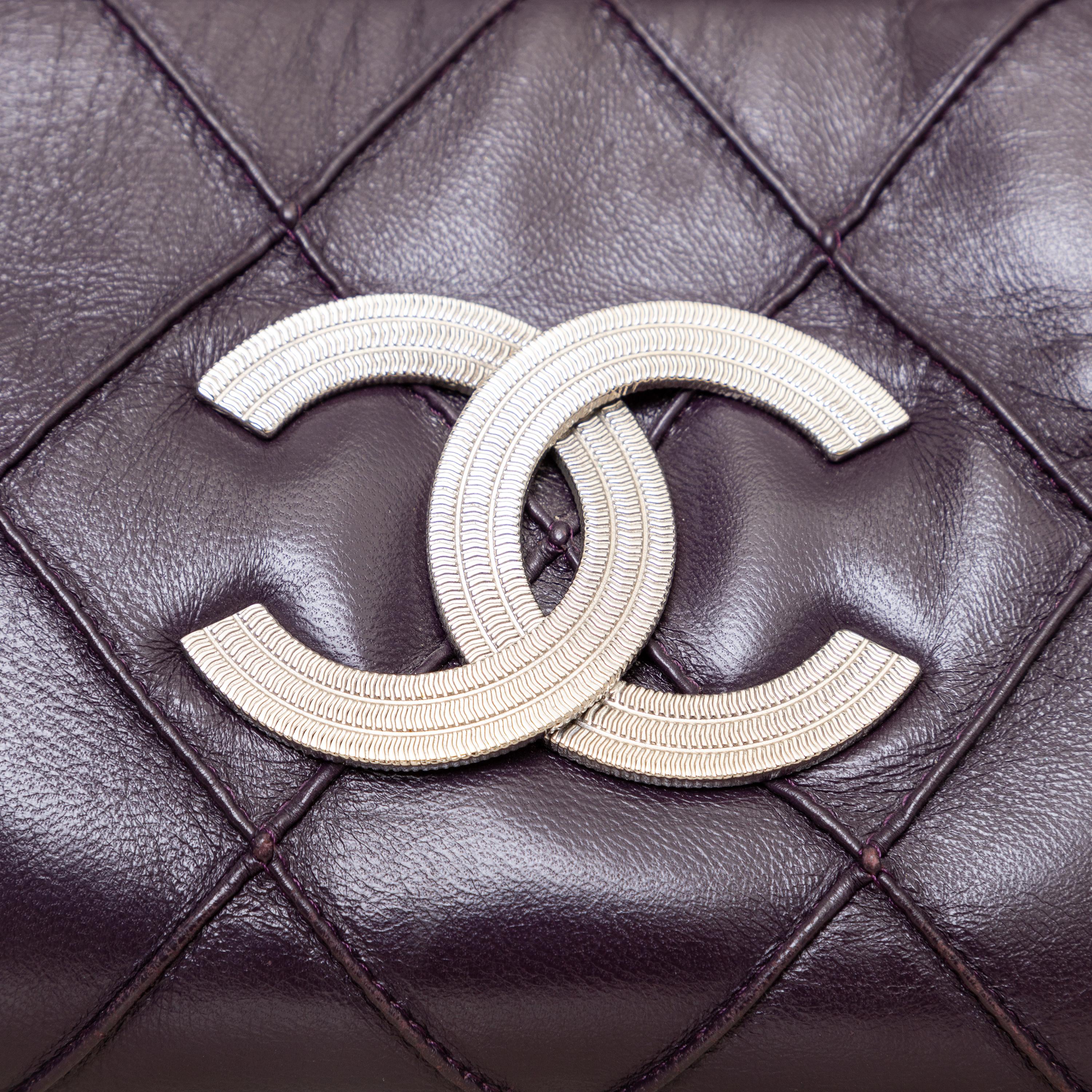 Experience luxury and style with Chanel's Lax Accordion bag. The deep plum color and silver-tone CC logo add elegance to any outfit. The silver chain-link strap with leather shoulder pad offers comfort and functionality. With multiple compartments