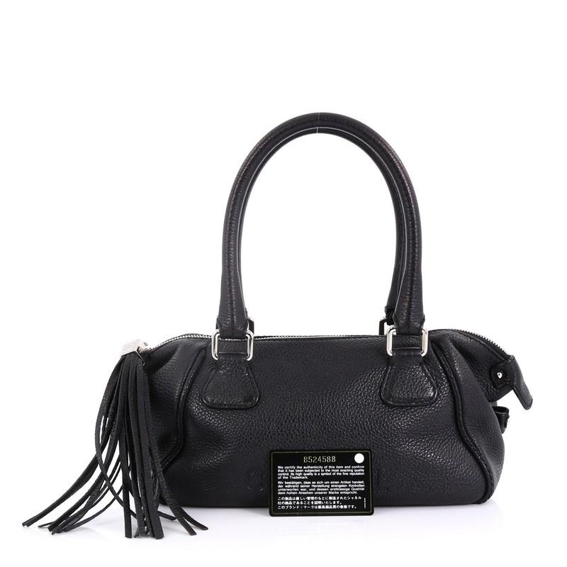 This Chanel Lax Tassel Bag Pebbled Leather Medium, crafted from black pebbled leather, features dual rolled handles, leather tassel, and silver-tone hardware. Its zip closure opens to a black fabric interior with side zip pocket. Hologram sticker