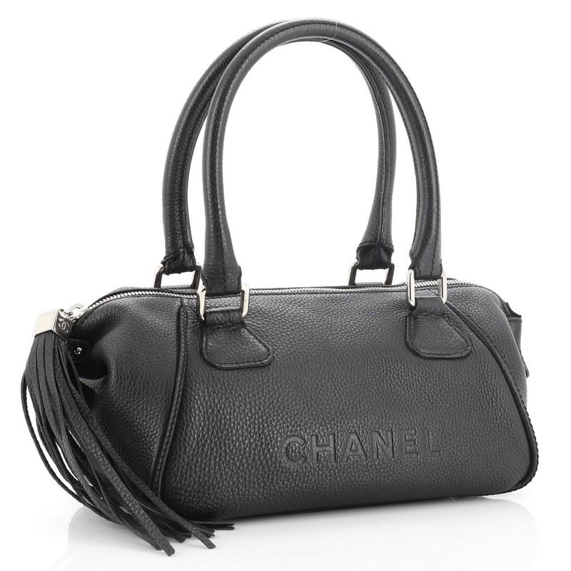 This Chanel Lax Tassel Bag Pebbled Leather Medium, crafted from black pebbled leather, features dual rolled handles, leather tassel, stamped Chanel logo, and silver-tone hardware. Its zip closure opens to a black fabric interior with side zip