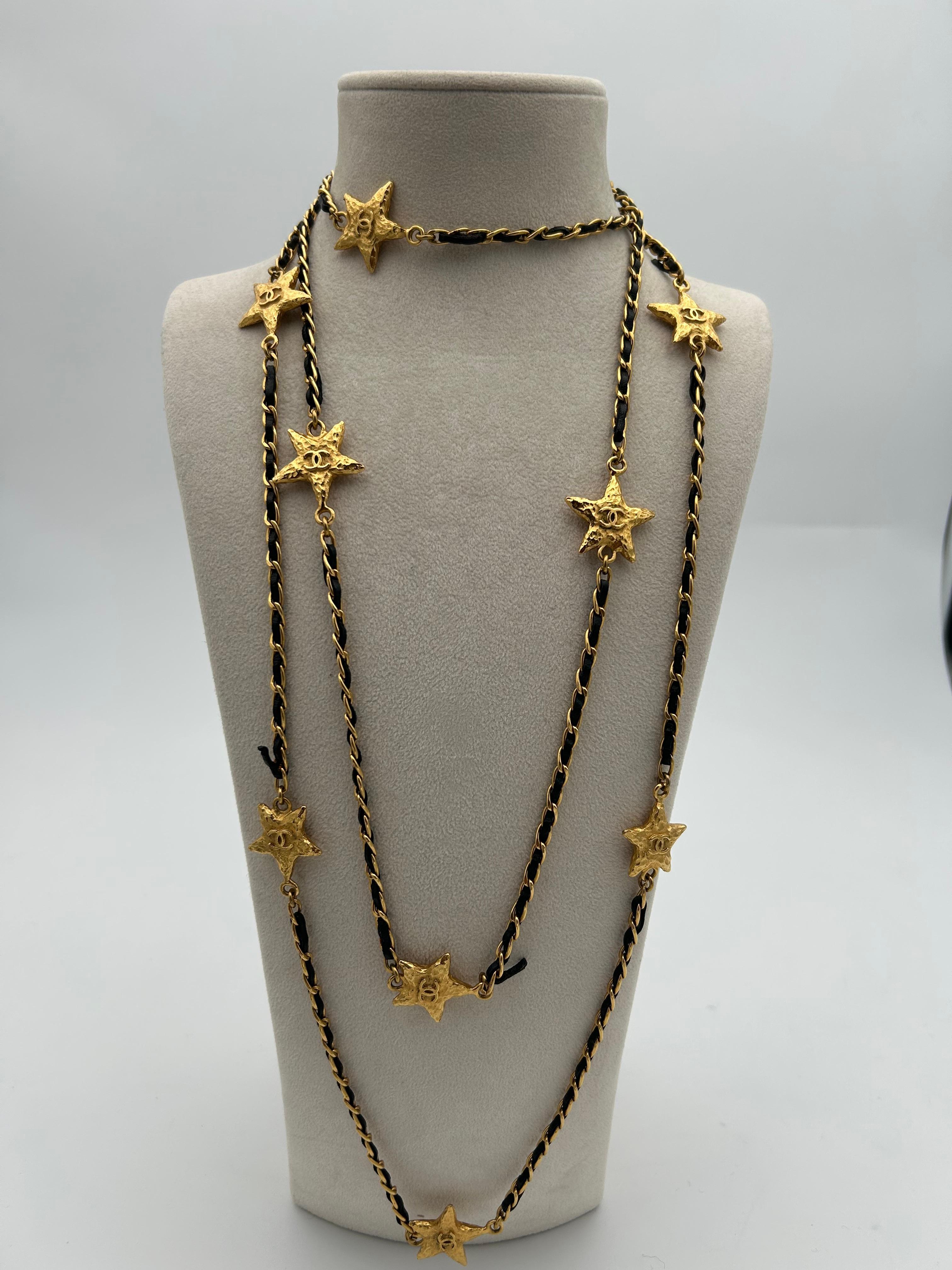 Chanel collana di stelle in pelle e catena dorata 2010. Bellissima collana vintage e iconica del 2010, questo articolo è un pezzo di spicco che eleverà ogni tuo outfit, sia di giorno che di notte. La lunghezza della collana è di 68 cm e può essere