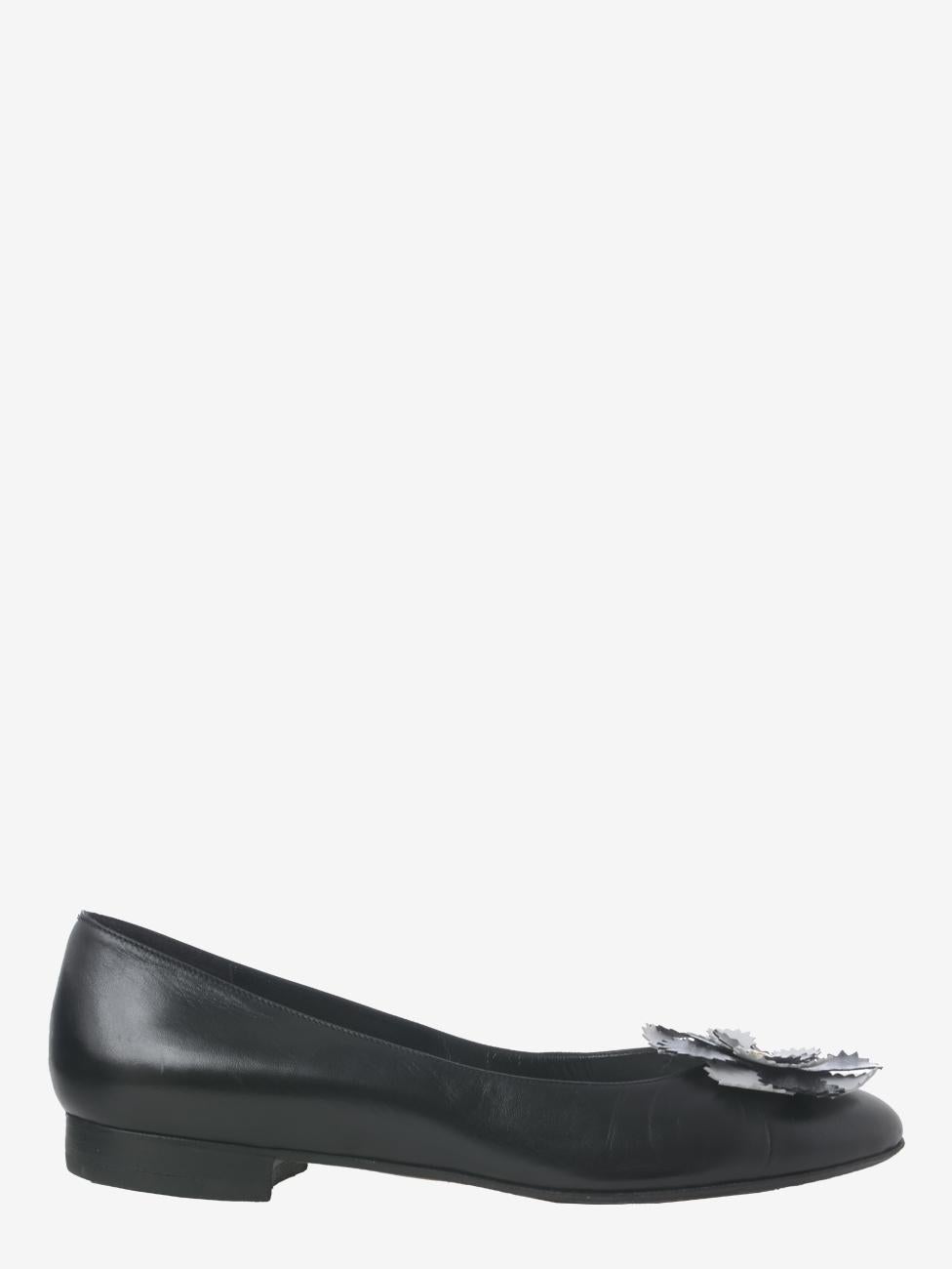 Chanel Leather Ballerina Shoes is an ultra-elegant pair of shoes featuring soft black leather and embellished with the brand's iconic camellia symbol, made of black and white leather with a gold logo in the center and placed on the round toe of the