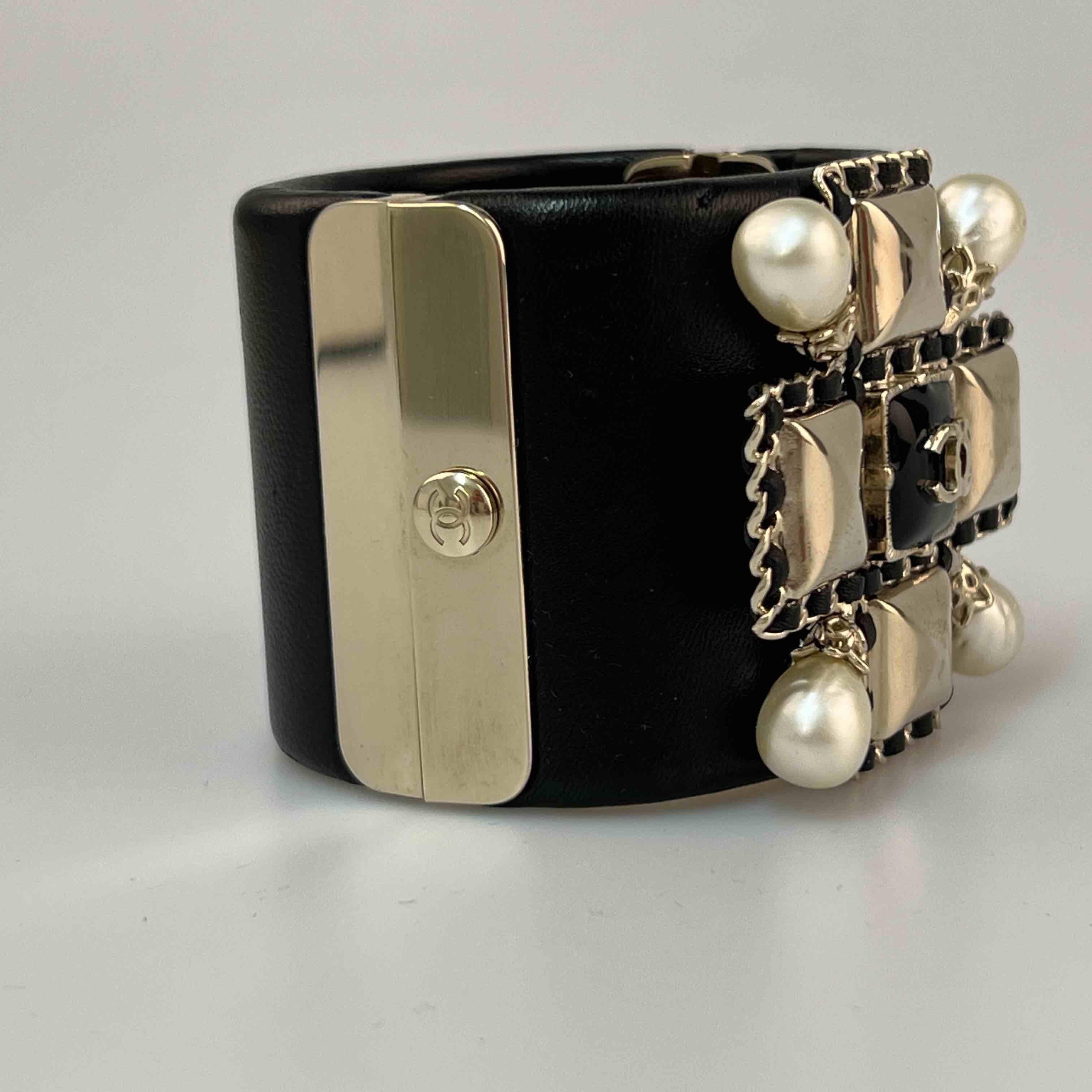 CHANEL cuff bracelet in black leather, gilt metal and pearls.
In very good condition.
Made in Italy.
Dimensions: height 5 cm, wrist circumference: 16.5 cm.
Stamp: yes.
Year: Spring 2020.

Will be delivered in its original box.