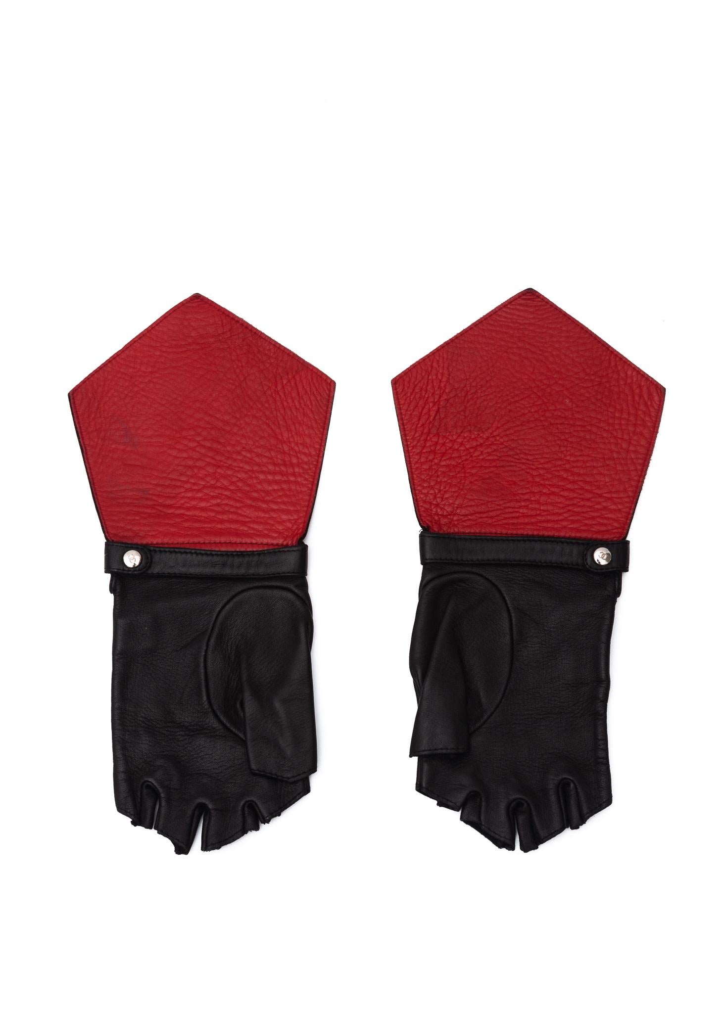 Black Leather fingerless gloves by Chanel. Fits Small. Red leather on the under side. Leather strap with a snap for fastening around wrist.

COLOR: black/red
MATERIAL: Leather
SIZE: Small
COMES WITH: Dust bag
CONDITION: Pristine - preloved item is