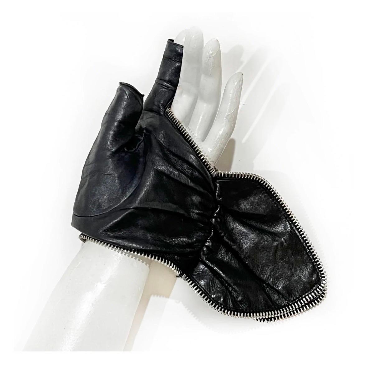 Leather fingerless gloves by Chanel
Made in France
Black 
Silver metal zipper seams
Decorative wrist wings 
Silver metal Chanel logo on each glove  
100% Leather
Condition: Great, preloved, normal leather wear 
Size/Measurements: (approximate, taken