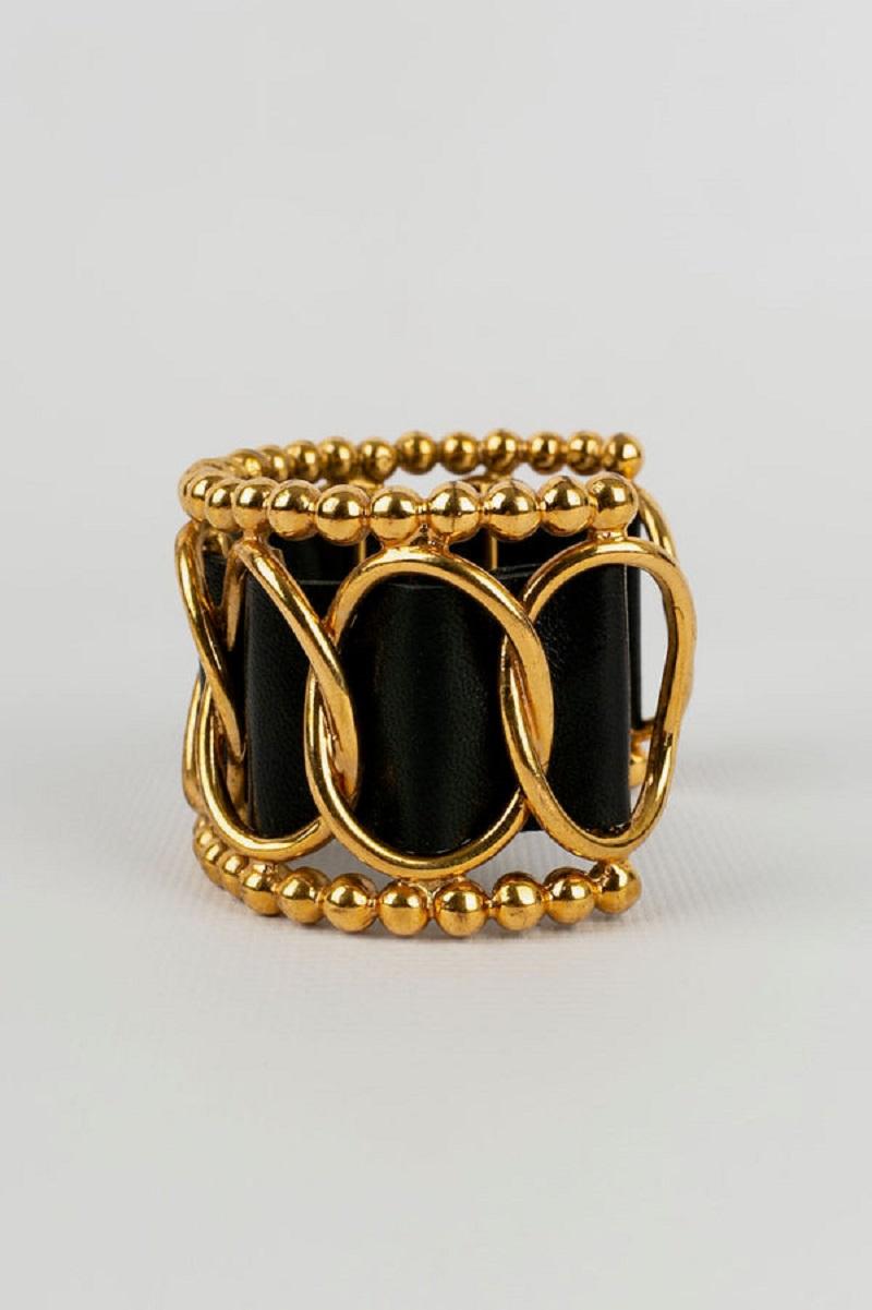 Chanel - (Made in France) Rigid bracelet in gold metal and leather. Collection 2cc8.

Additional information:
Dimensions: Circumference: 13.5 cm 
Opening: 3 cm 
Width: 4.3 cm
Condition: Very good condition
Seller Ref number: BRAB13