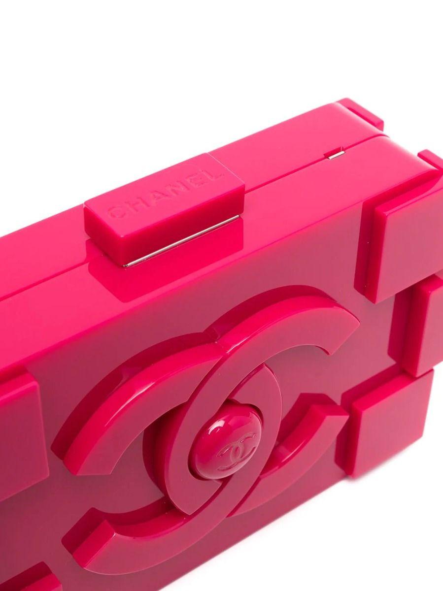 Chanel's playful lego clutch gets a fierce upgrade. This rare and collectable clutch bag is formed of fuschia plexiglass. Featuring prominent logos across both sides of its hard-case facade and its push closure on top, this piece is a must for any