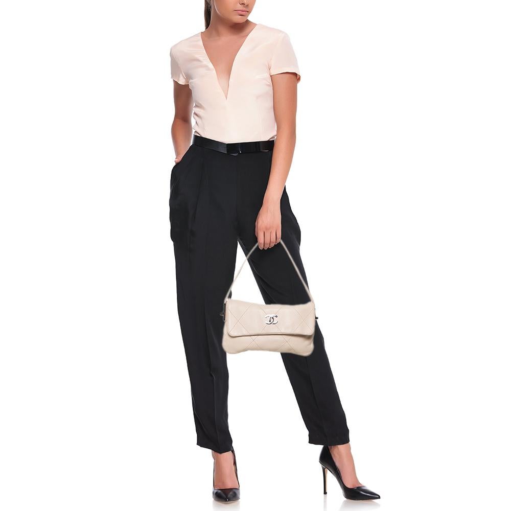 The beauty of this bag from Chanel lies in its structured silhouette, refined lines, and understated appeal. It is fashioned out of leather, offset by a silver-tone CC logo on the front flap. The bag's shape will work well with tailored outfits and