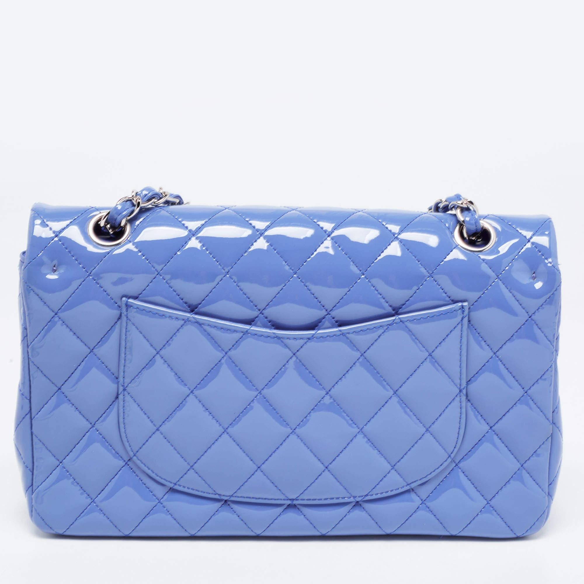 The Chanel Classic Double Flap Bag exudes timeless elegance and sophistication. Crafted from luxurious patent leather, this iconic piece features signature diamond quilting, a double flap design, and a gleaming silver-tone chain strap. It is a