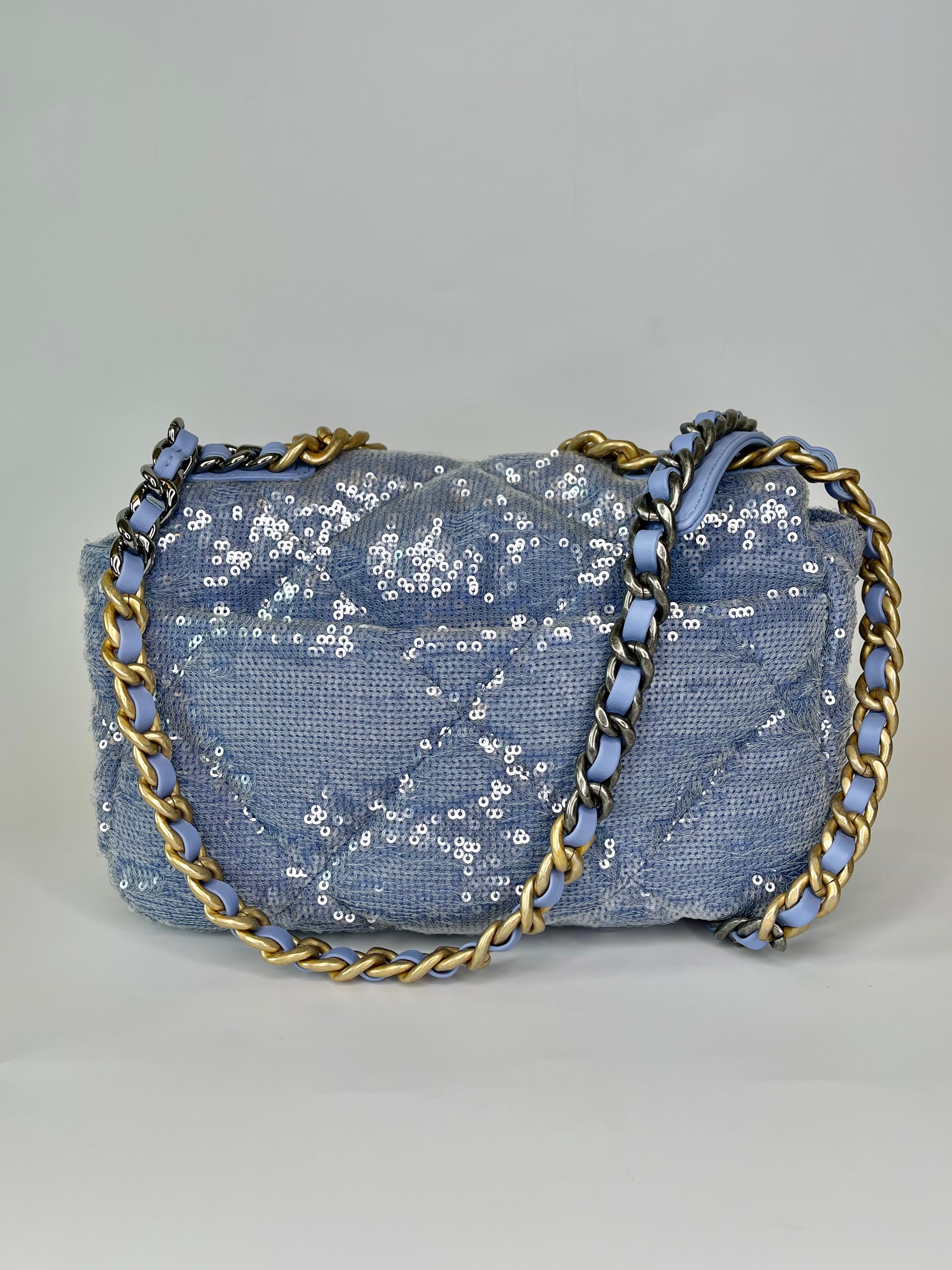 This shoulder bag is made of light blue circular sequins on a base of light blue fabric. The bag features blue leather threaded silver, ruthenium, and an aged gold chain link shoulder straps with a leather threaded aged gold Chanel 19 CC turn lock