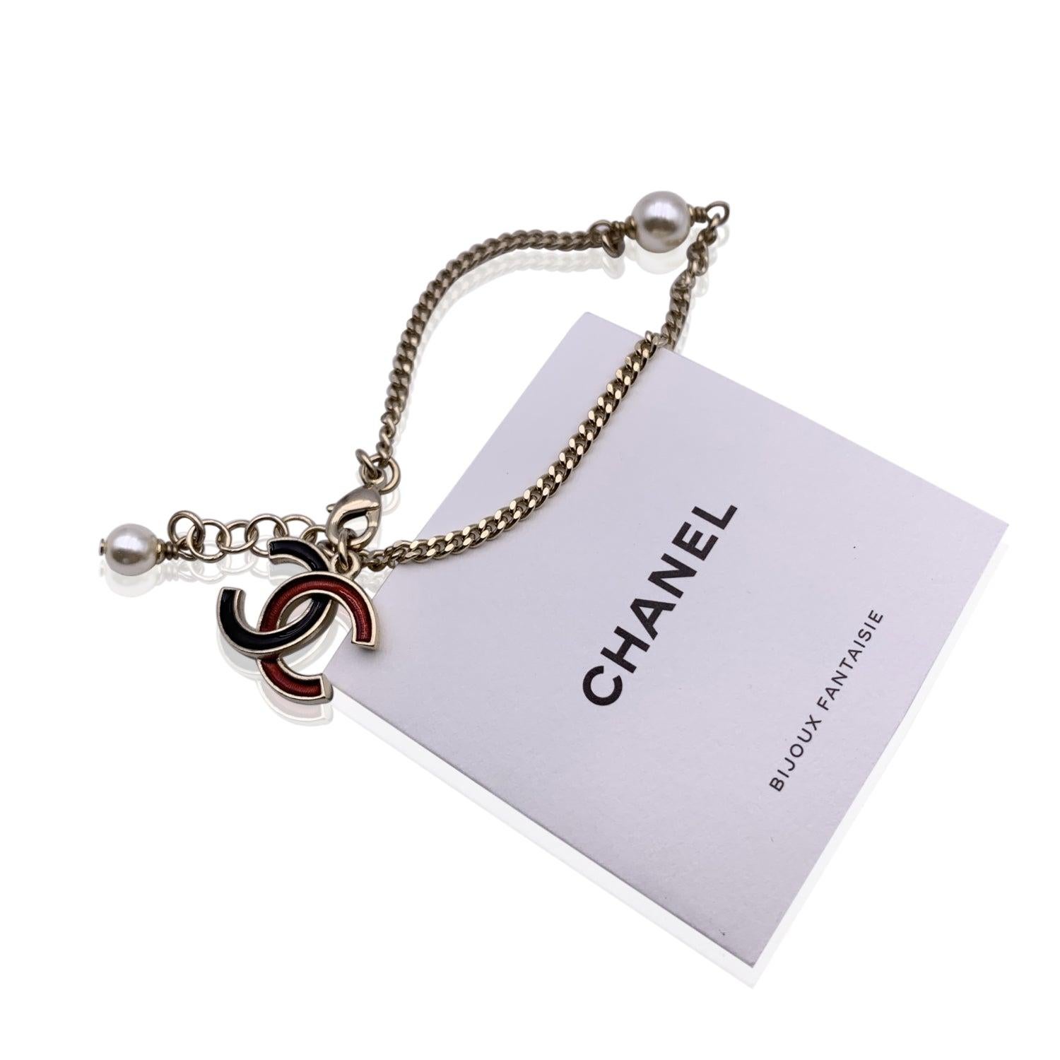 Lovely light gold metal chain bracelet with enameled CC logo charm in black and red, by CHANEL from the 2018/2019 collection. 2 small faux pearls accents. Lobster closure. Marked 'Chanel C18 CC A made in France' on the closure Total lenght: 7.5