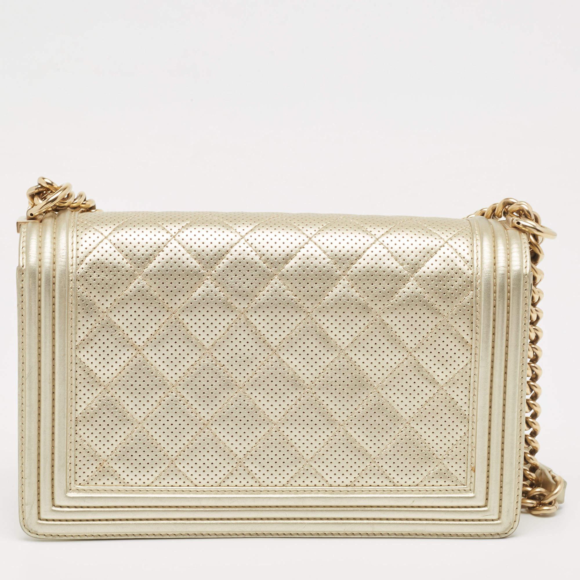 The Chanel New Medium Boy Bag exudes timeless elegance with its light gold hue and meticulously stitched quilted leather. The iconic Boy bag design features a gold-tone chain strap and the distinctive Boy clasp, making it a luxurious and stylish