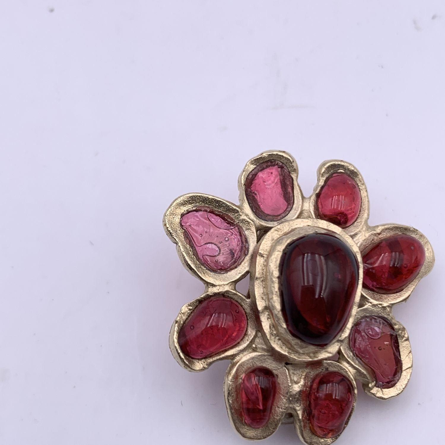 Beautiful flower earrings by CHANEL. They are finely crafted in gold metal with red glass cabochon. Small CC logo on a petal. 'CHANEL - 07 CC A- Made in France' oval tag on the reverse of the earring. Diameter: 2.2 cm Condition B - VERY GOOD Two