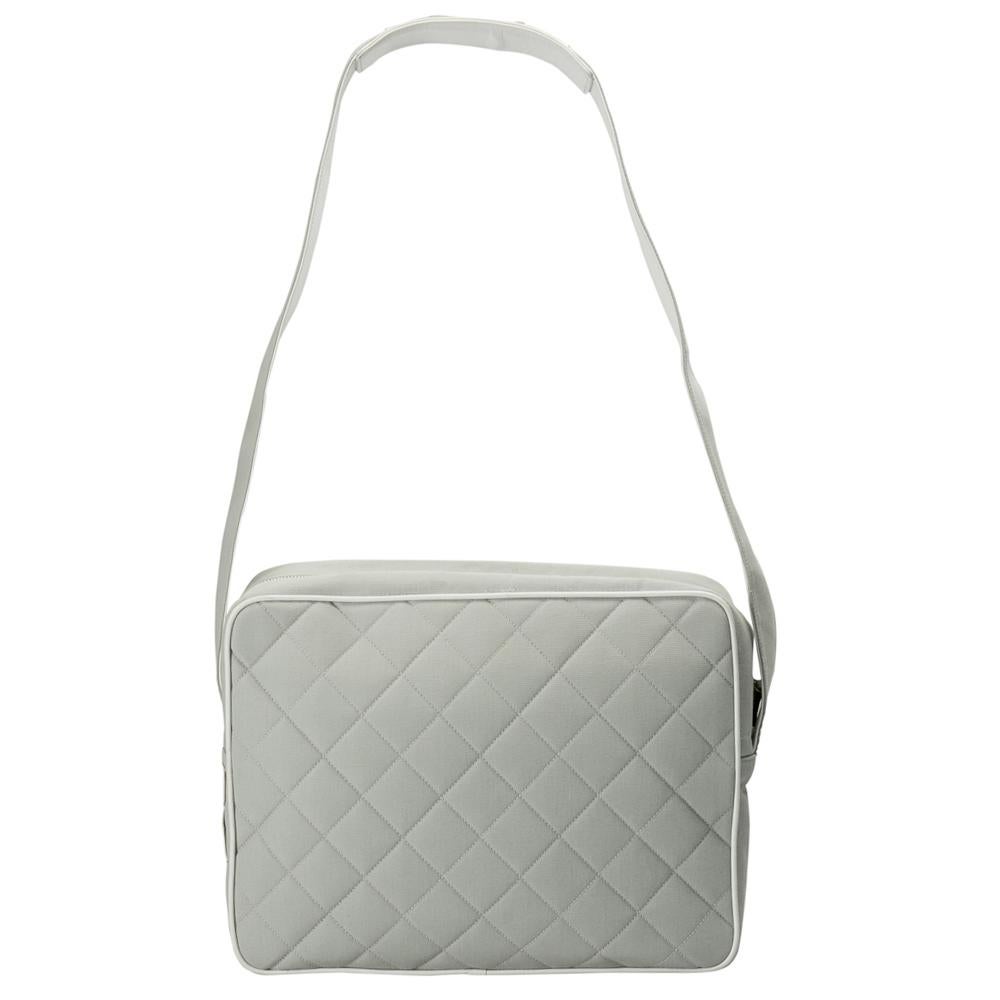 A Chanel classic, this messenger bag is a must have. Crafted from grey canvas and leather trims, it is stitched with the brand's signature quilted design on the exterior. The exterior has the Chanel lettering on the front and a flat shoulder strap.