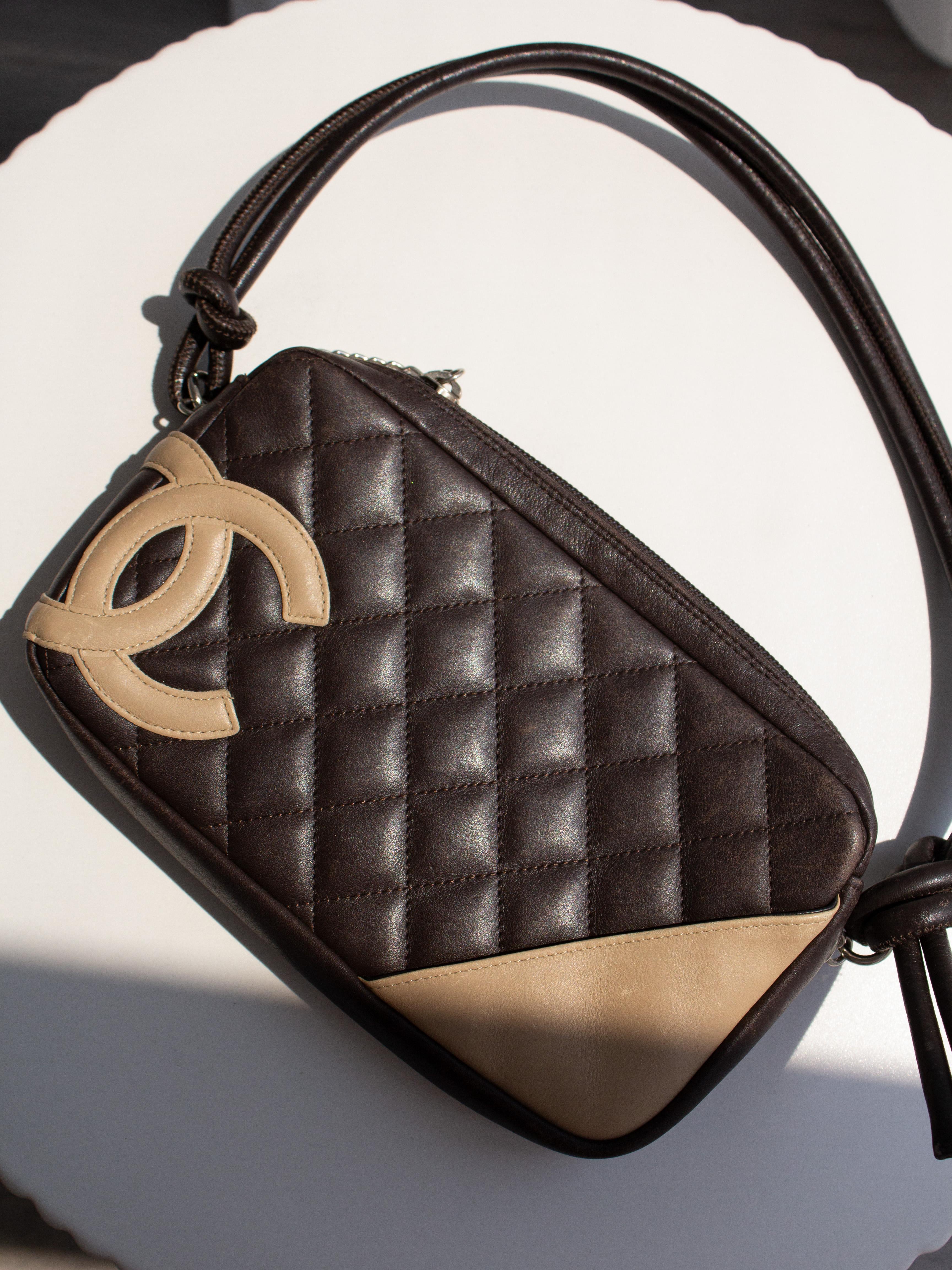 Chanel Cambon Ligne Umhängetasche aus dunkelbraunem, gestepptem Leder mit beigem CC-Logo und Eckdetails. Mit einem geknoteten Lederriemen, einem Reißverschluss mit Logo-Charme und einem Steckfach auf der Rückseite.
Diese seltene Farbvariante aus der