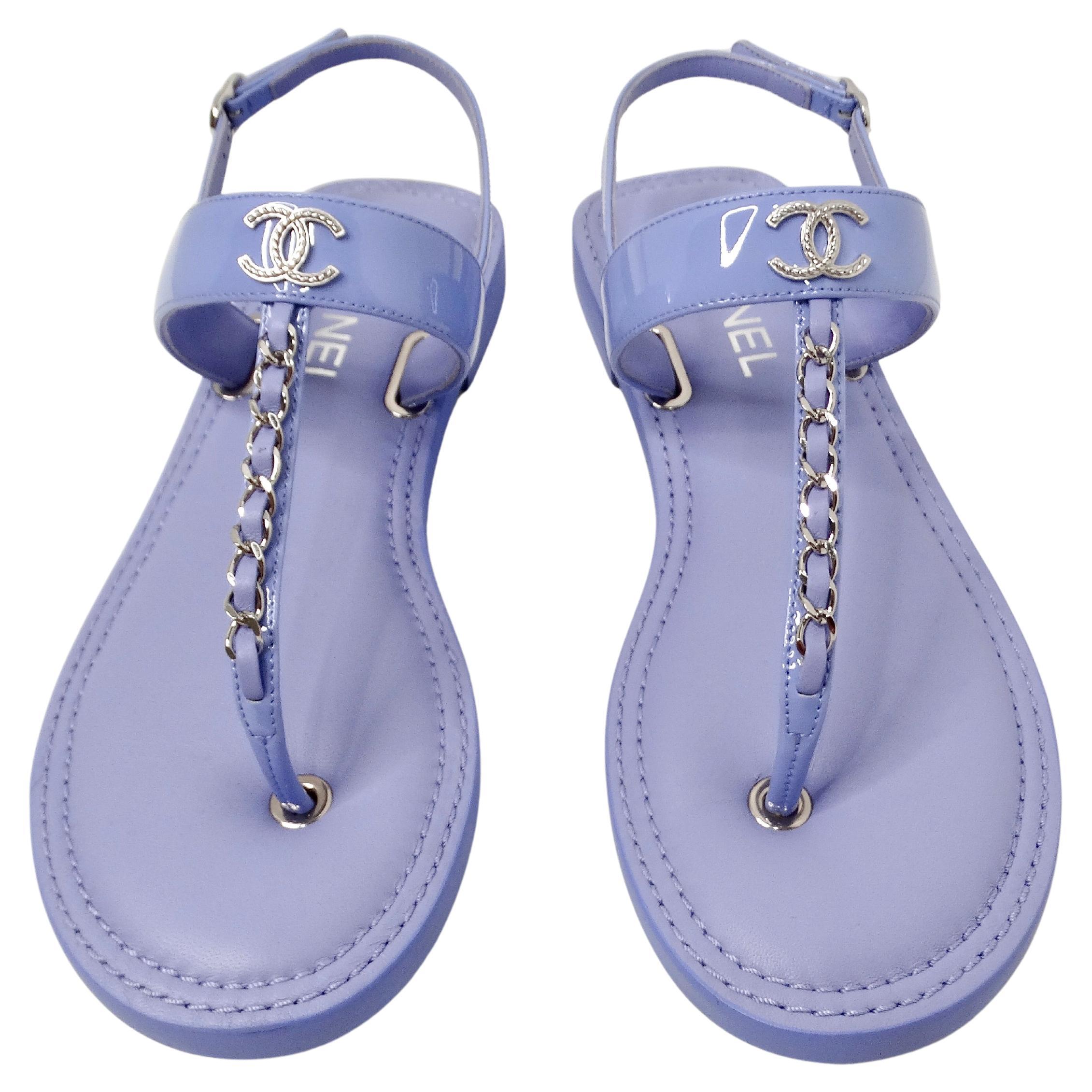 The Chanel Lilac Patent Leather Chain T-Strap Sandals are a stunning embodiment of luxury and sophistication. Crafted from glossy lilac patent leather, these sandals exude a vibrant yet elegant charm, perfect for elevating any ensemble. The T-strap
