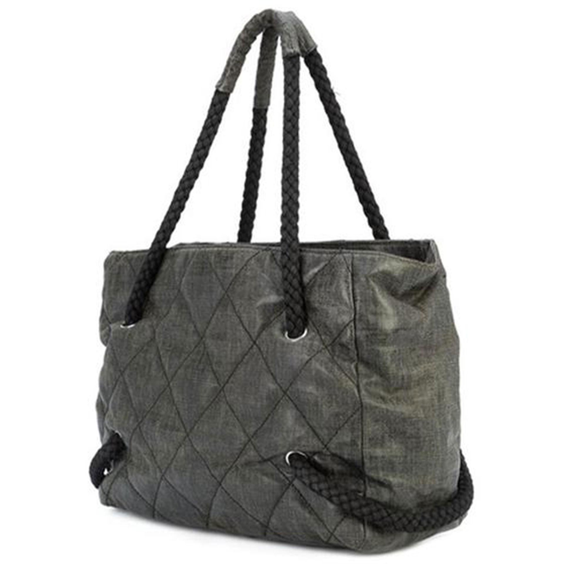 This gorgeous rare Chanel Cruise Tote is made of black coated canvas, braided handles, an open top design, a main internal compartment with zipped pockets, a diamond quilted finish, silver-tone hardware and a large white wooden interlocking CC logo
