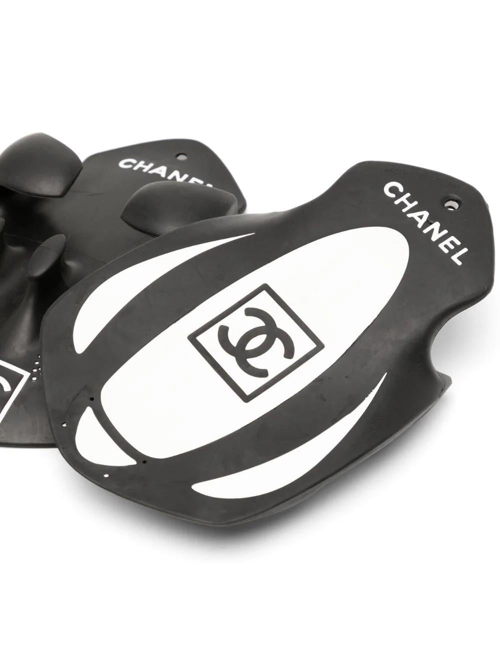 Crafted in France from a blend of charcoal black synthetic rubber and Thermoplastic Polyurethane, this pair of pre-owned, limited edition swimming peddlers by Chanel features its iconic interlocking CC logo and 'Chanel' motif on both the front and